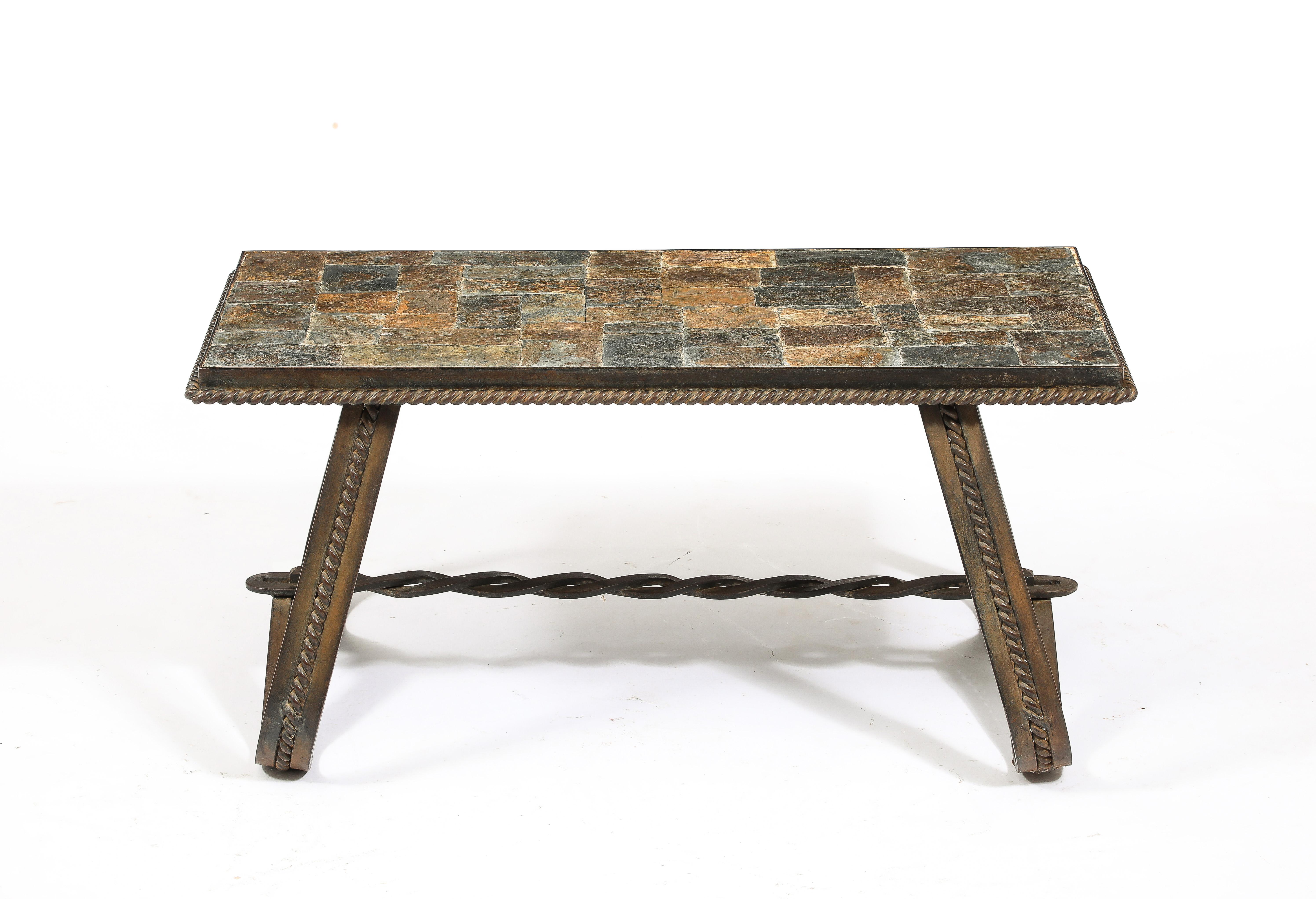 Table basse graphique en fer forgé et fer battu ferronnerie présentant un plateau en mosaïque d'ardoise. Magnifiques détails d'entretoise en forme de chaîne. 
En bon état vintage, patine et oxydation sur la base. Peut être remis en état moyennant un