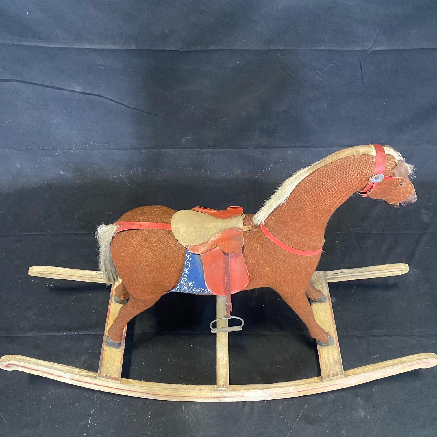 Wonderful 19th century nursery rocking horse having charming detailed head with a dished face and flared nostrils. He retains his original saddle and leather stirrups and is mounted on a wooden base. This horse is in a good condition, with wear