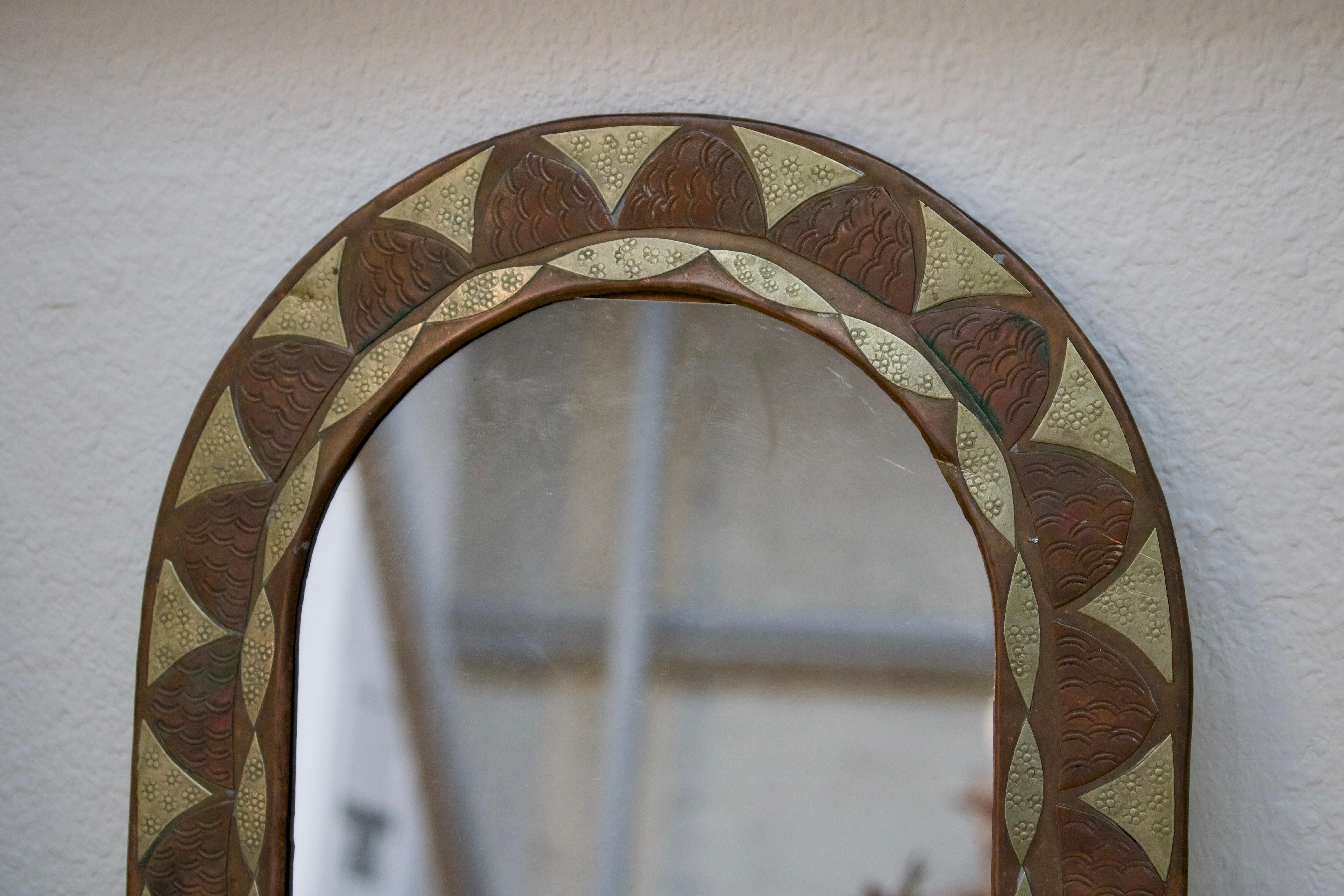 This ornate “Feuille” (leaf) mirror is a genuine French treasure showcasing impeccable artisanal craftsmanship. The distinct alternating petal design creates a sophisticated rhythm around the frame, where the warm patinated copper elements harmonize