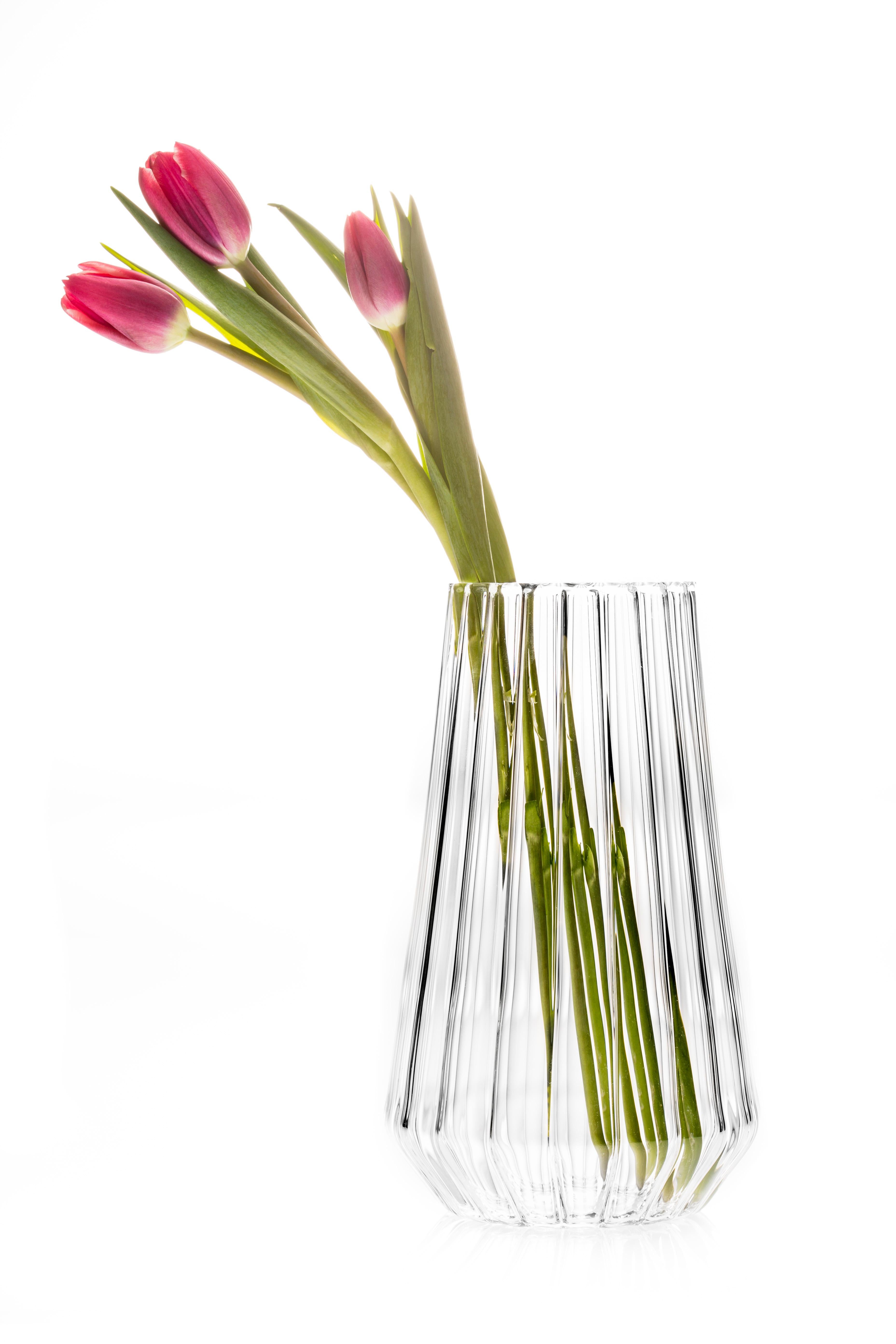 STELLA MEDIUM

Pure in form, the lenticular effect of the fluted glass masks the stems and showcases the flower heads. The facet near the bottom serves as a marker for the water line and keeps
the visual effect of the vase is clean and minimal.

The