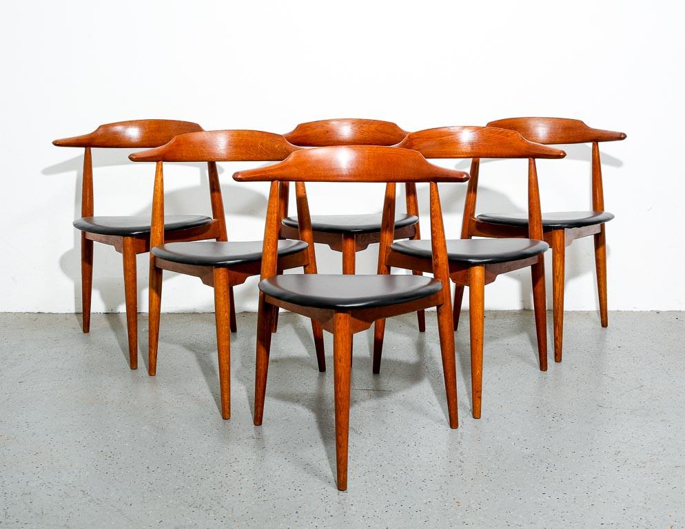 Vintage set of 6 dining chairs by Hans Wegner for Fritz Hansen, Denmark. Three-legged design with oak frame and newly upholstered black leather seats. Signed with a stamp, 'FH' on frame. Measure: 17
