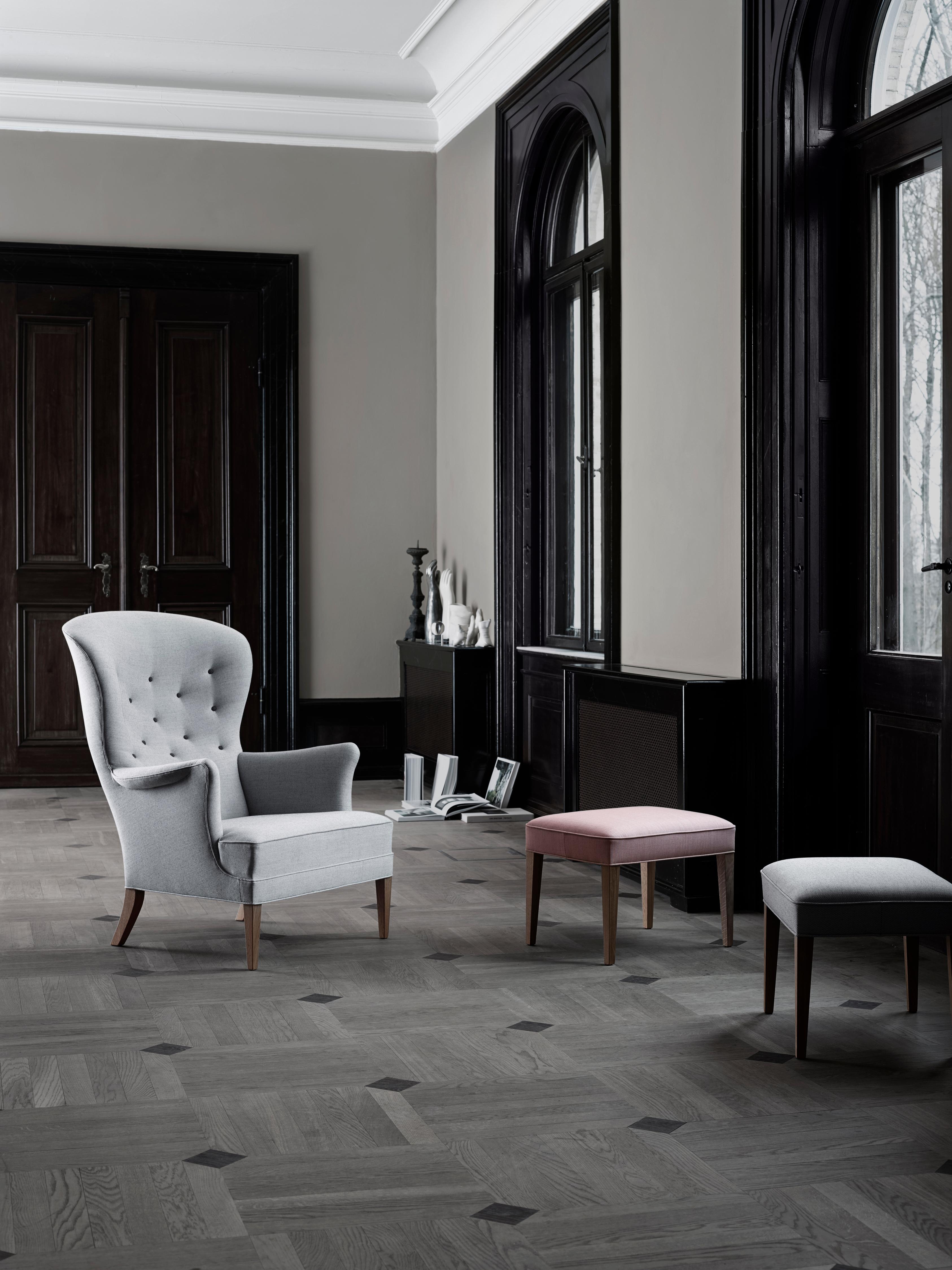 The FH420 heritage footstool by Frits Henningsen has a robust and classic air of tranquility about it. With solid wooden legs and upholstered detailing, it was designed to match the Heritage chair, but it also works equally well on its
