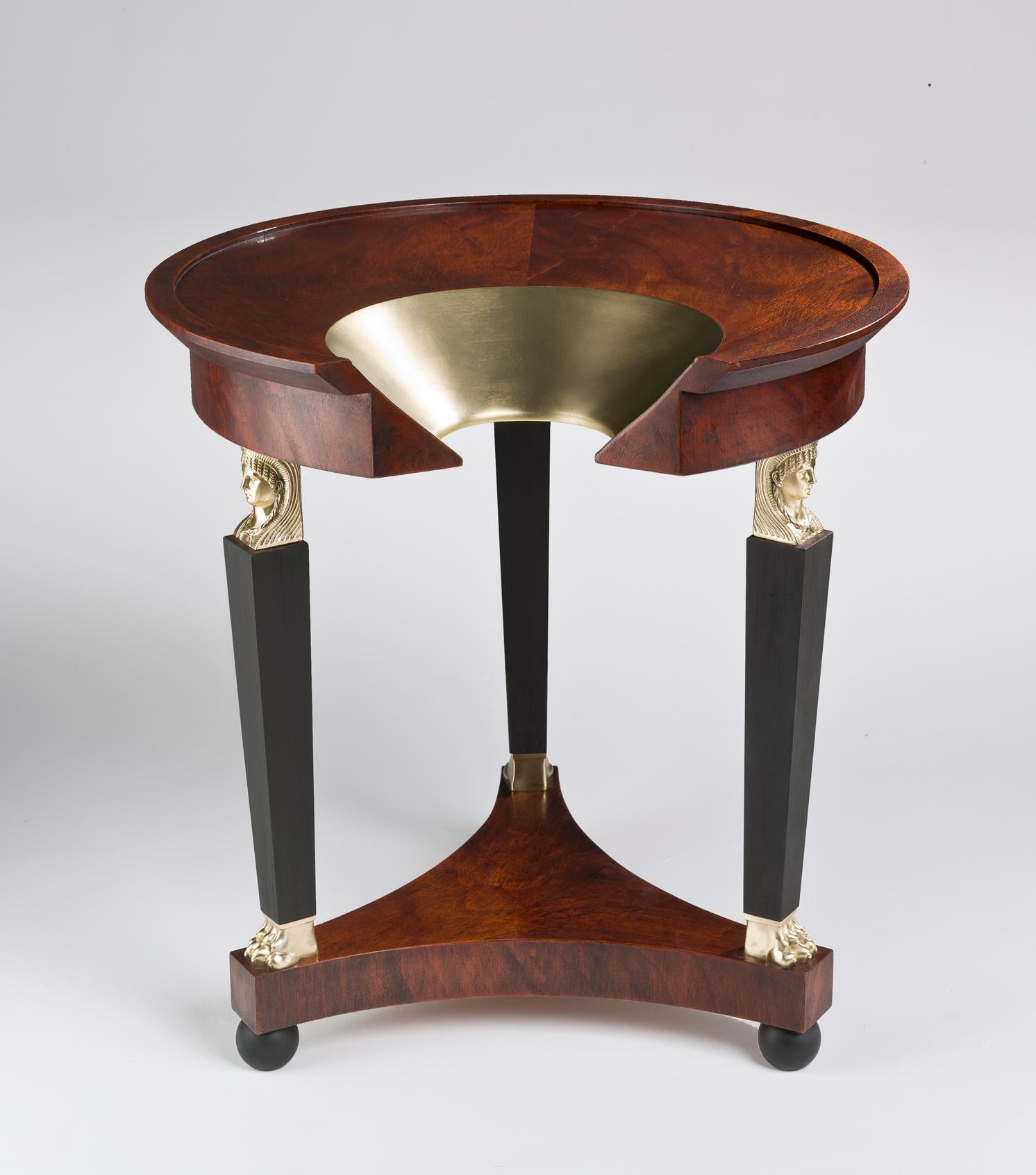 The F* Hole Gueridon side table by Ferruccio Laviani is covered by dark feather Mahogany. 
To its classic taste and proportions, decorative details are added, golden designs and carved columns forming the three legs of the table. 

Gracefulness and