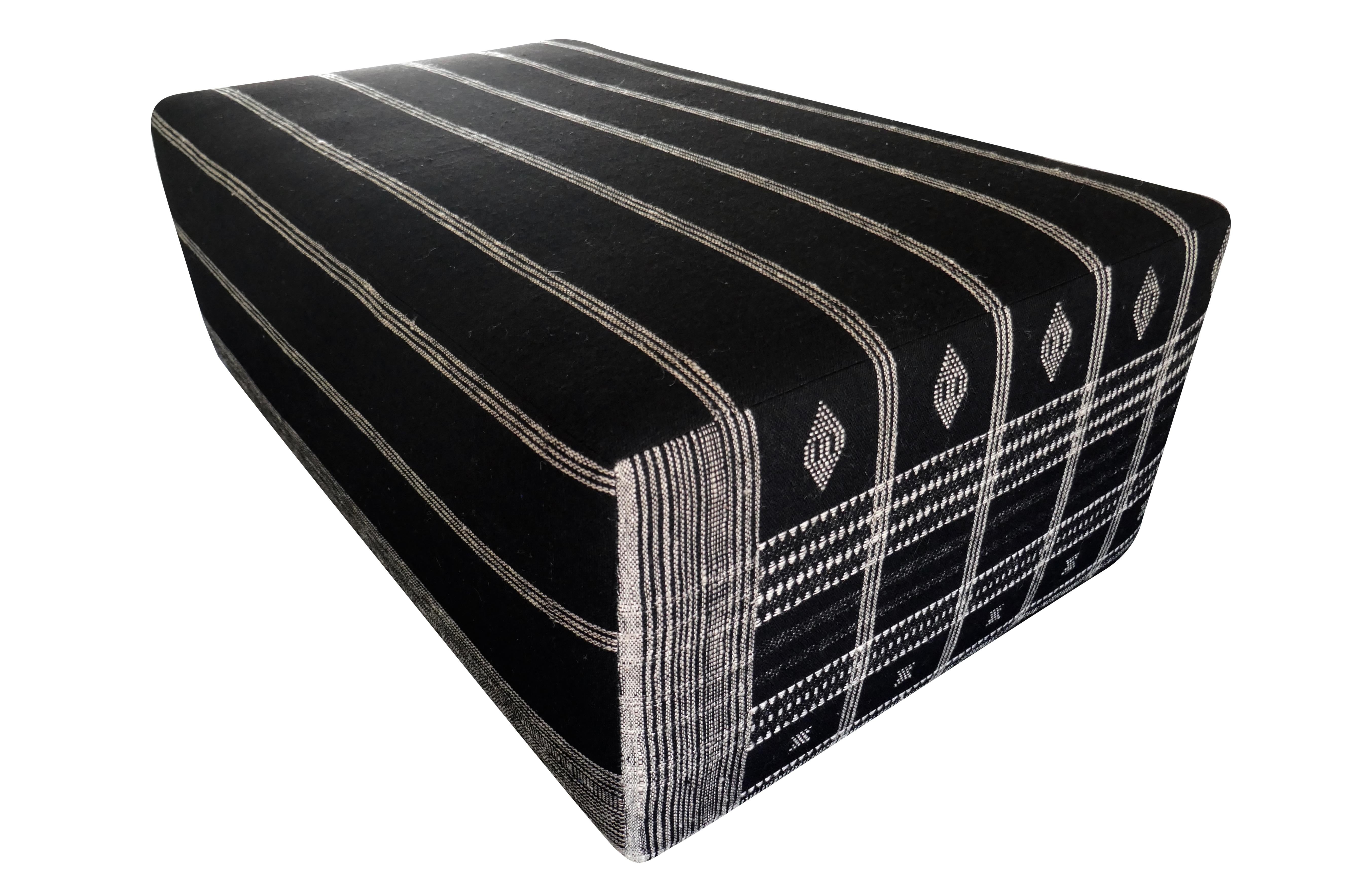 FI large cocktail style ottoman, perfectly upholstered in beautiful authentic hand-woven & embroidered heavy textural Berber tribal organic black wool textile. Fully cushioned with a solid wood inner-frame, variable embroidered pattern on each side.