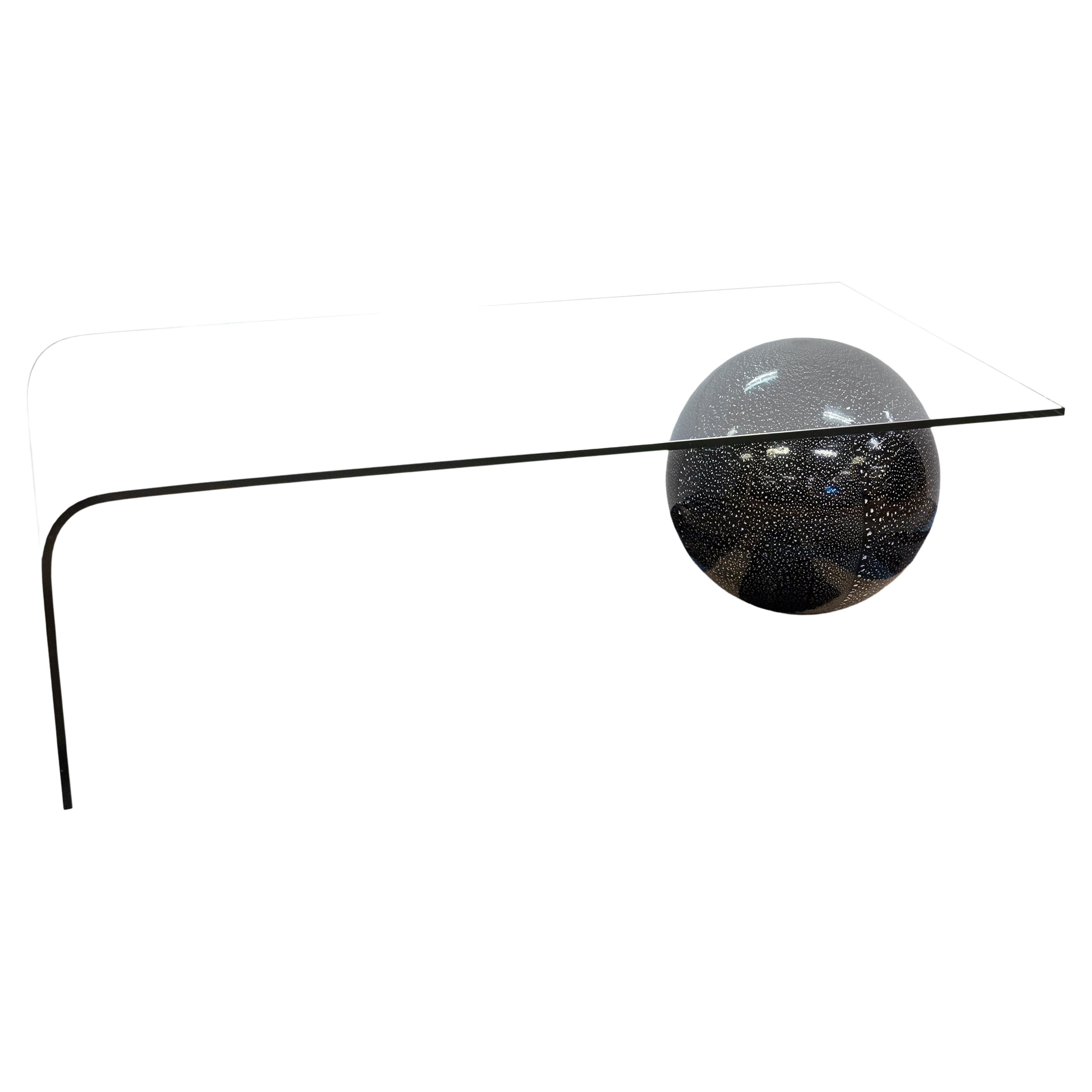 A Fiam Italia waterfall cocktail coffee table with black sphere base. This super cool postmodern 1980s coffee table has an iconic, timeless design. This piece features a glass waterfall design, with one side rounded, and the other with angular
