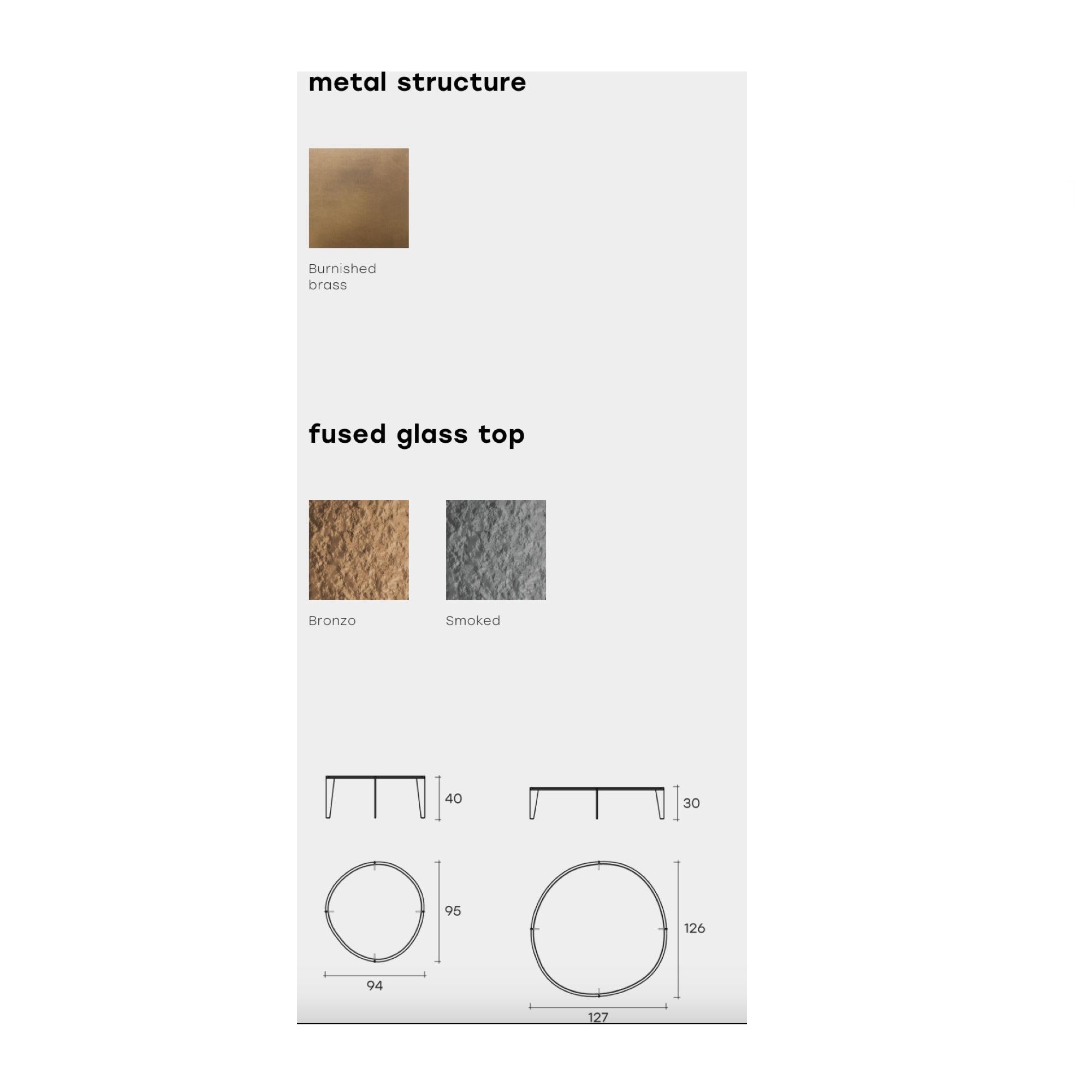 Table basse avec plateau en verre fusionné et trempé de 10 mm, finitions fumé ou bronze.

Le plateau est également disponible en marbre.

Base métallique en finition laiton bruni.
capacité de charge sur le dessus : 30 kg