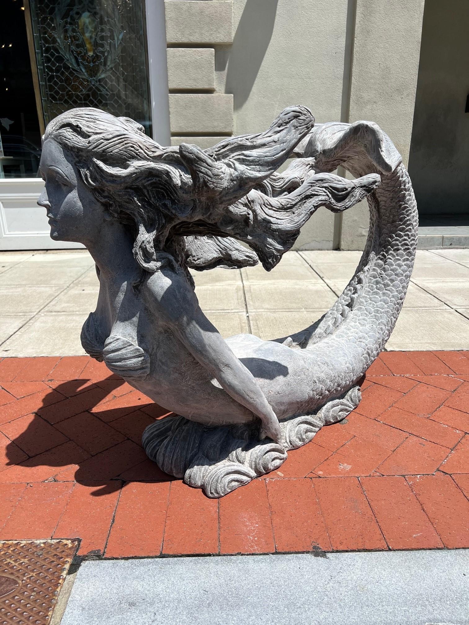 Beautiful mermaid statue with long flowing hair and a large tail, perfect by a pool or ocean view. The mermaid can also be used as a interior table base with a glass top inside of your home. It's made of a very durable fiberglass in its natural gray