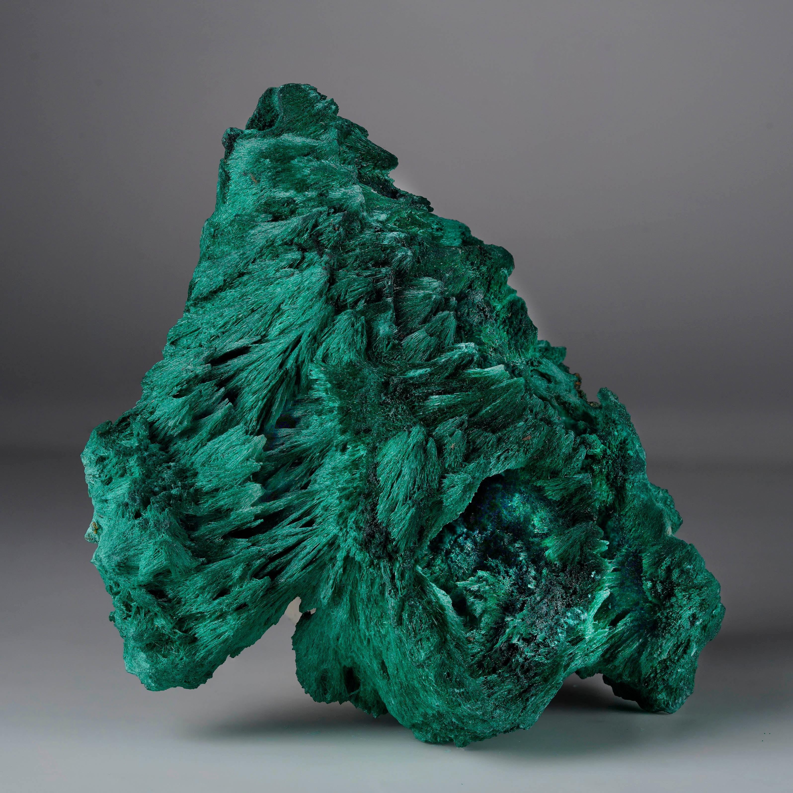 Questa sorprendente malachite fibrosa mostra un intenso colore verde smeraldo e una struttura dinamica che la rende visivamente affascinante da ogni angolazione. L'intricata crescita a bande o fibrosa conferisce al pezzo una notevole profondità e