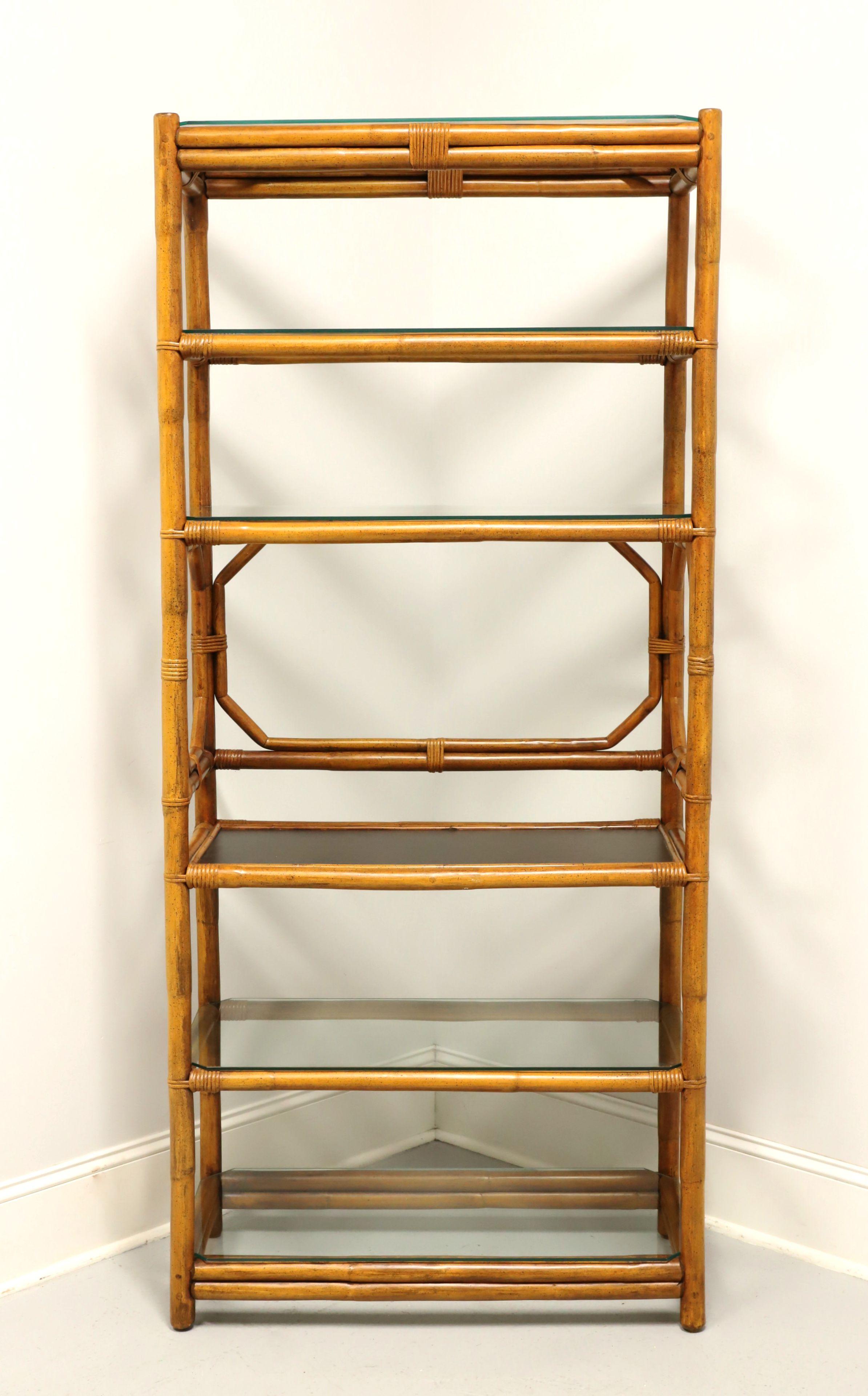 A Coastal style etagere / shelving unit by Ficks Reed. Faux bamboo with decorative open frame, rattan accent strapping and octagonal shaped accents to center. Features six fixed shelf areas, five with removable glass shelves including the top and