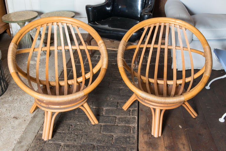 Pair of Mid-Century Modern Ficks Reed circular saucer form swivel lounge chairs designed by John Wisner. In a natural finish.
 