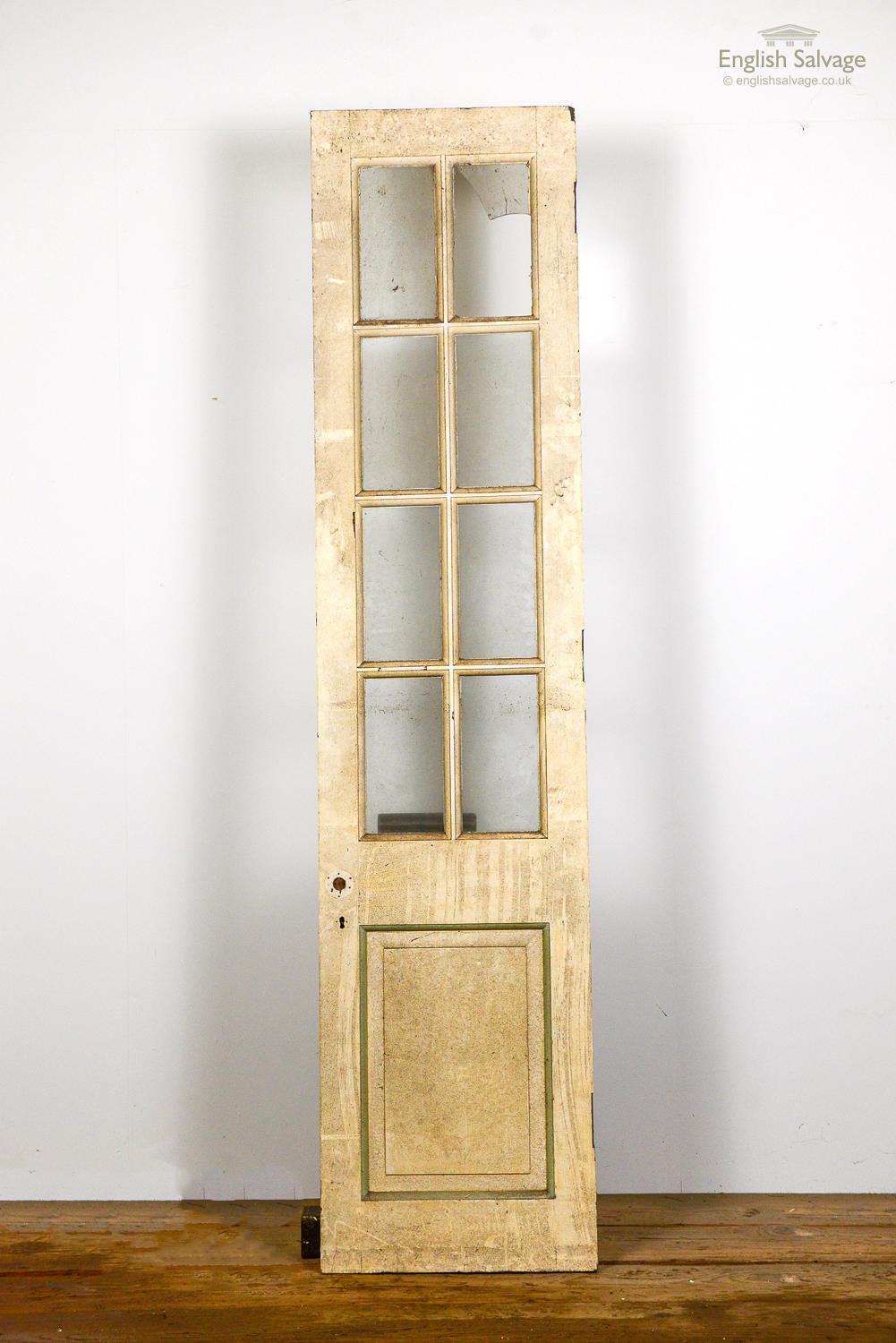 Salvaged sturdy single panel glazed door. Painted hardwood with eight glazed panels over one beaded and fielded panel. One pane is broken. Scuff marks and chips to the paint.