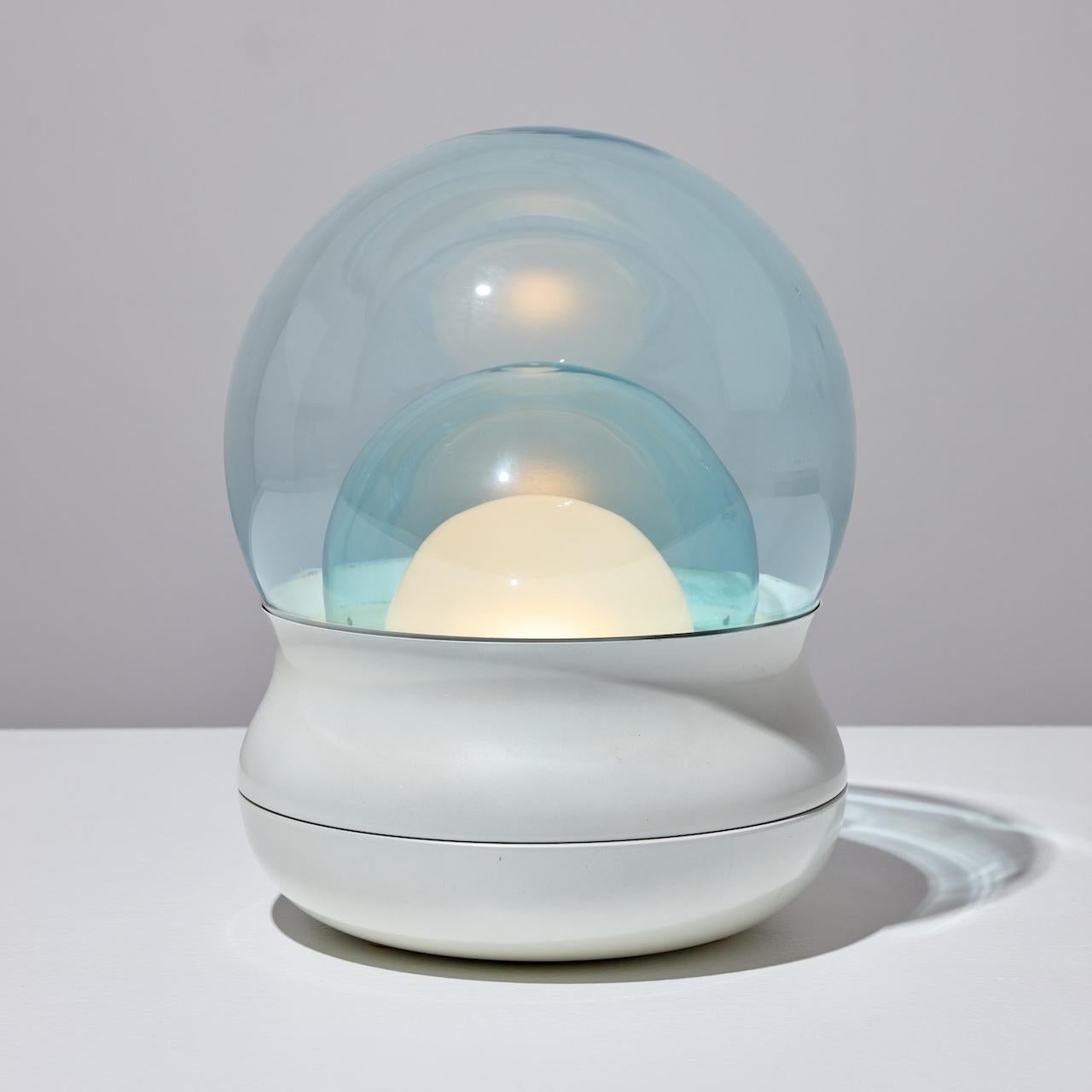 'Fiesta' Table Lamp by Giorgio Longoni for Stilnovo (IT, 1969)

Stacked cut blue glass bubbles with a final frosted diffuser are secured by a compression molded plastic base. The illumination is visually relaxing, subtle but striking. One E27 socket