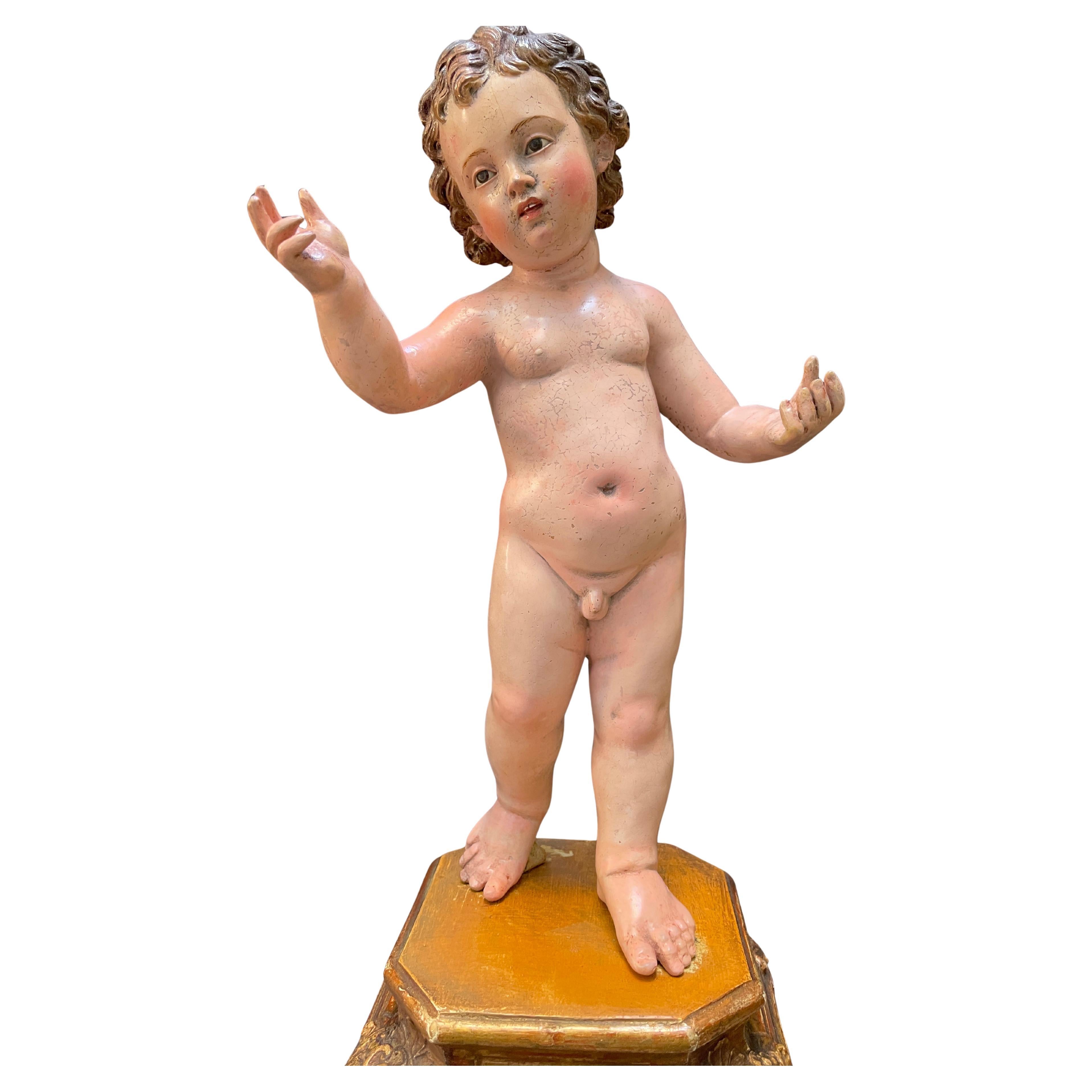 Sculpture en terre cuite de l'Enfant Jésus du XVIIIe siècle, figure italienne d'art sacré et de dévotion polychromée représentant l'Enfant Jésus debout sur un piédestal de forme carrée en bois sculpté et doré à la feuille d'or. Ce plateau de