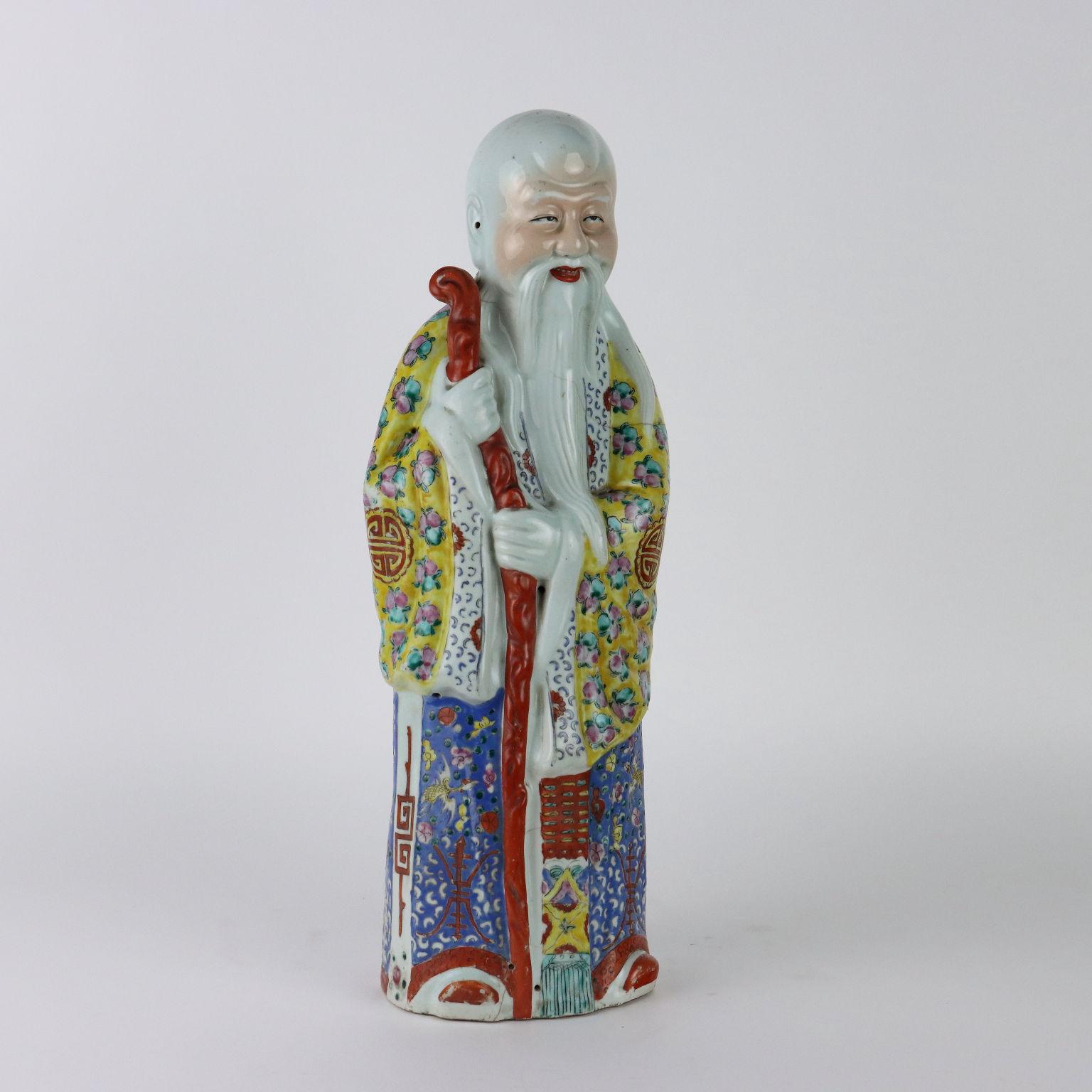 Polychrome enamel-painted porcelain figure depicting the immortal Shou Xing. The robe richly decorated with stylized ideograms and peaches symbolizing longevity. Oval Ji Maosheng mark embossed under the base. 