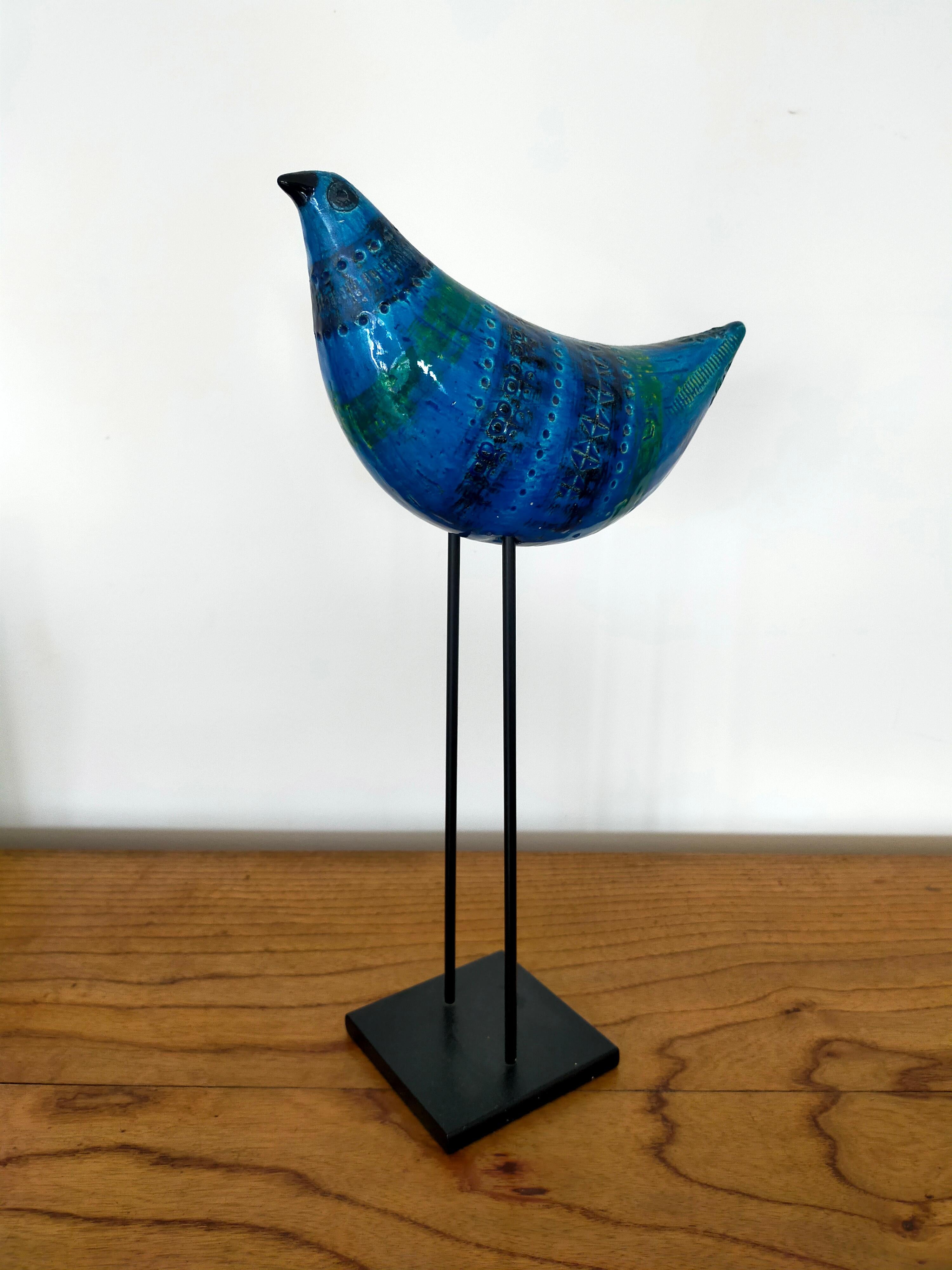 Blue ceramic bird on iron black basement engraved by hand and enamelled in bright blue and green colors with their characteristic patterns. 
Marked 