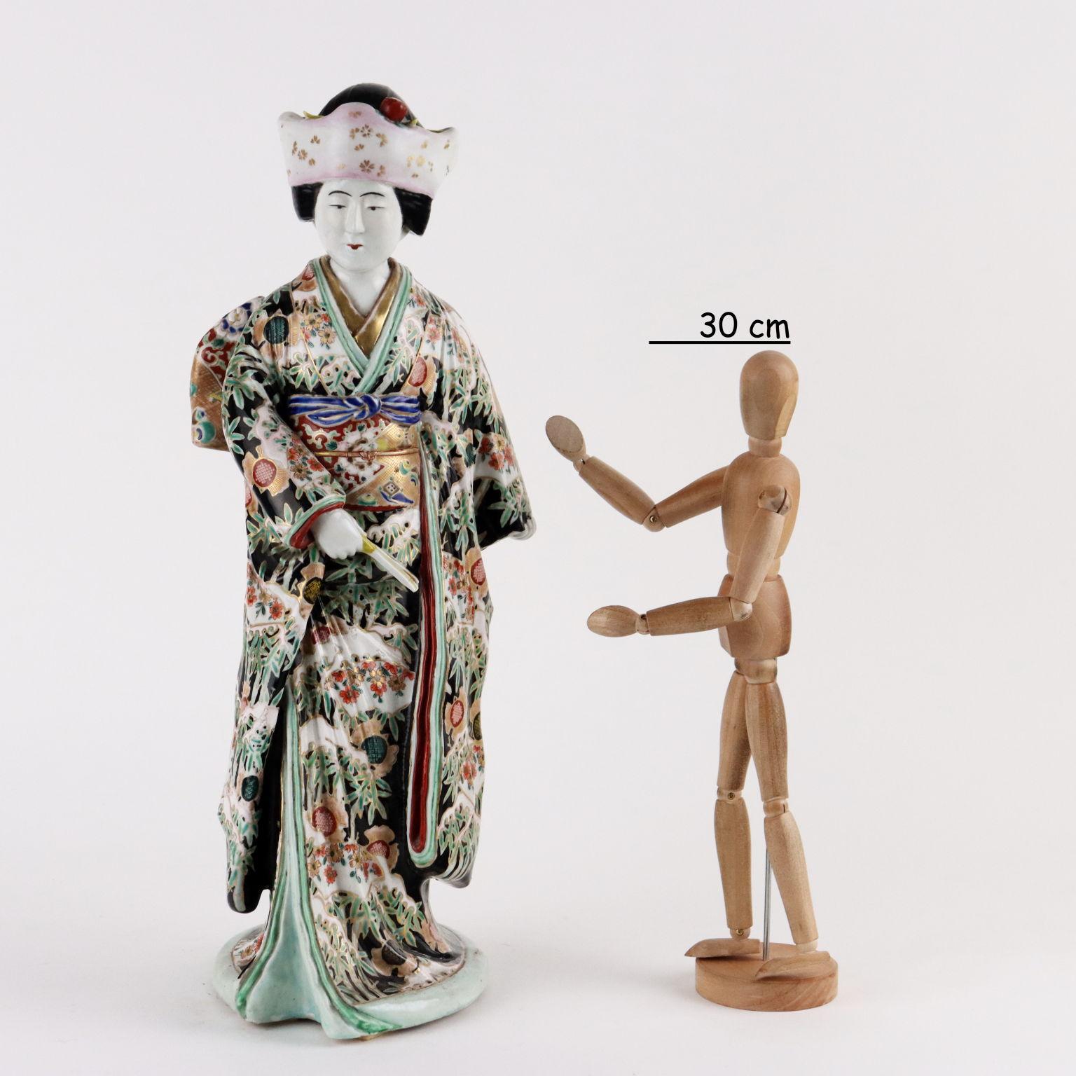 Figura in porcellana Kutani dipinta a smalti policromi, raffigurante una bijin con kimono riccamente decorato a simulare un broccato in parte lumeggiato in oro. Giappone fine epoca Meiji.