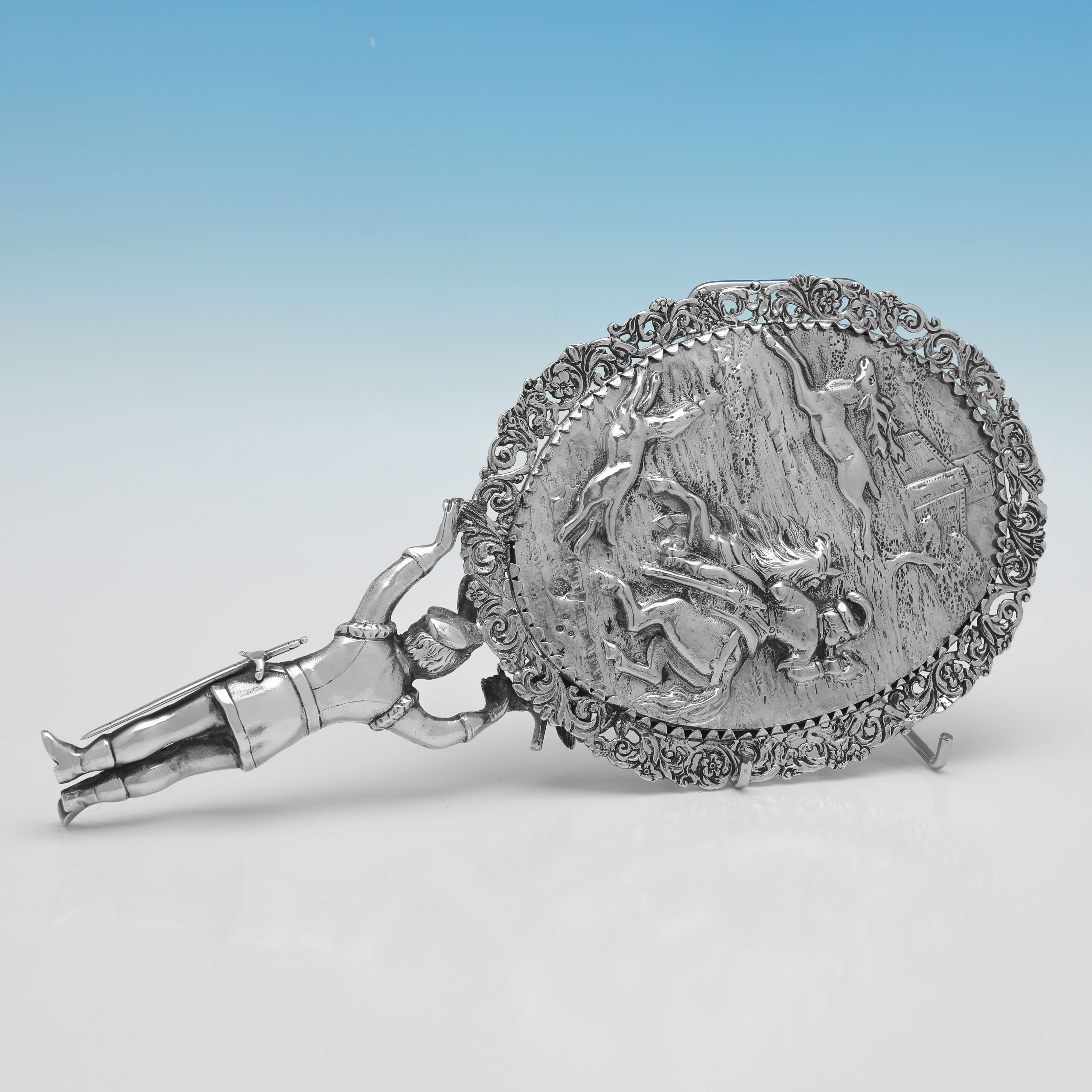 Hallmarked in London in 1882 by Edward Brown, this charming, Antique, Sterling Silver Hand Mirror, features a figural handle, and a chased scene to the reverse. 

The hand mirror measures 10.5