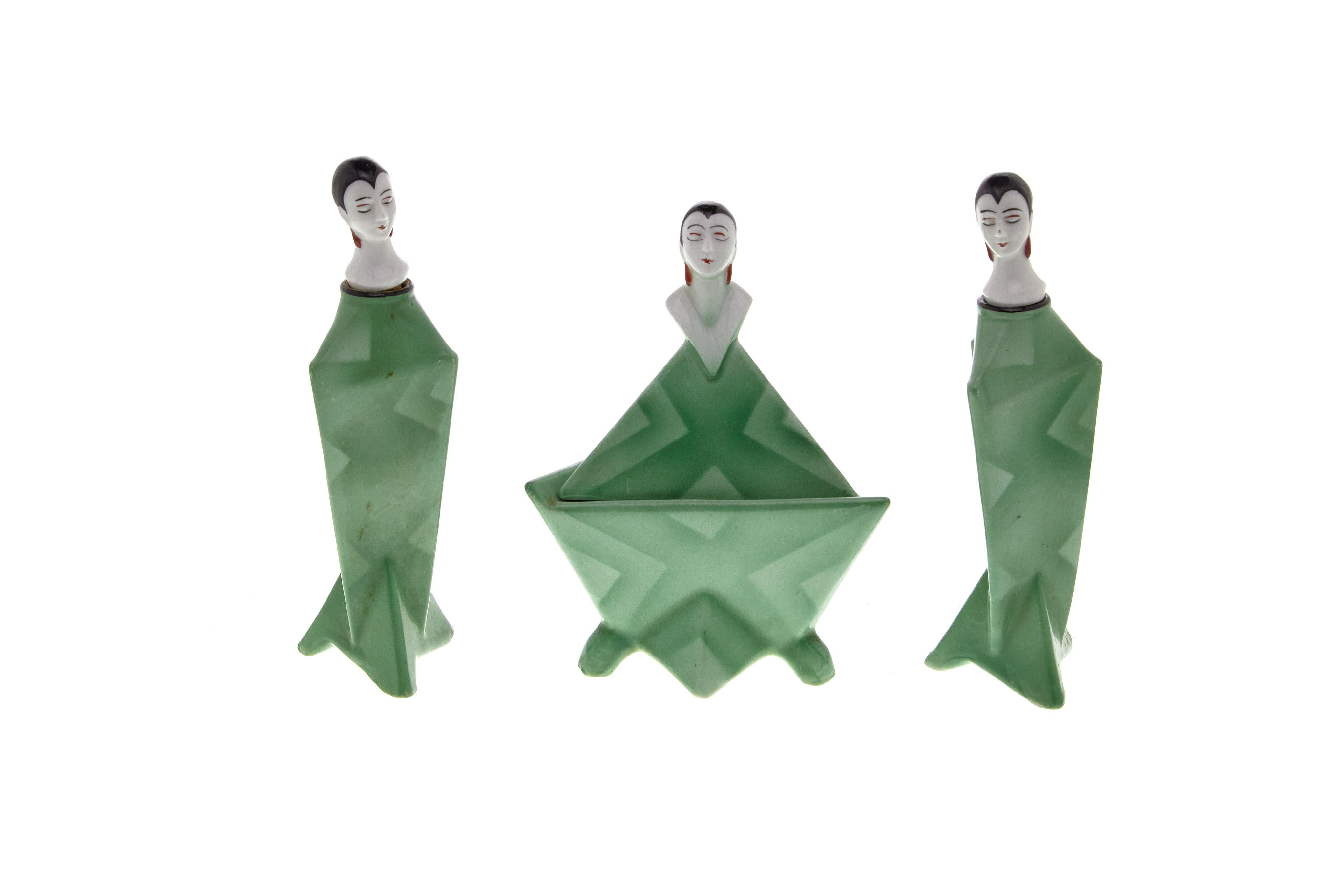 A set of 2 porcelain perfume bottles and a powder box, each in the form of a woman. Painted in a beautiful Art Deco pattern. Marked Germany.
 