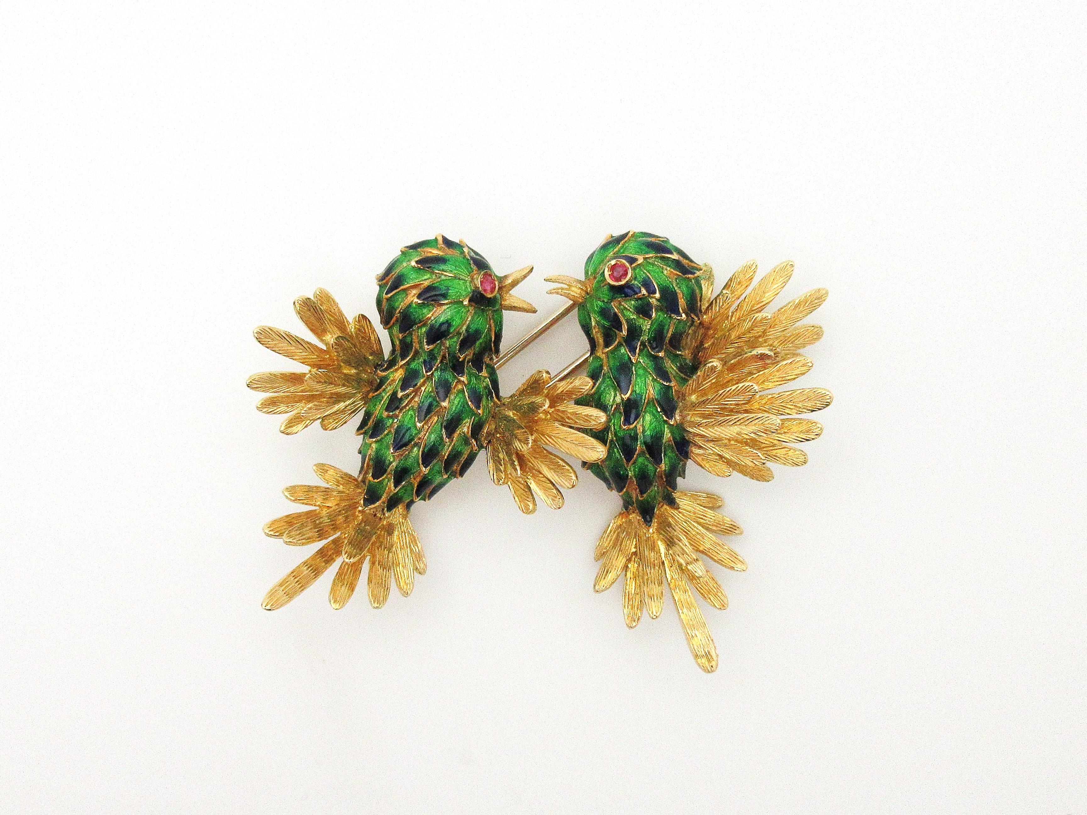 This beautiful vintage brooch depicts two playful birds in 3D.  The birds are crafted from solid 18k yellow gold, with detailed feathers containing shades of green and cobalt blue enamel creating an ombre effect.  The wings and tails are expertly