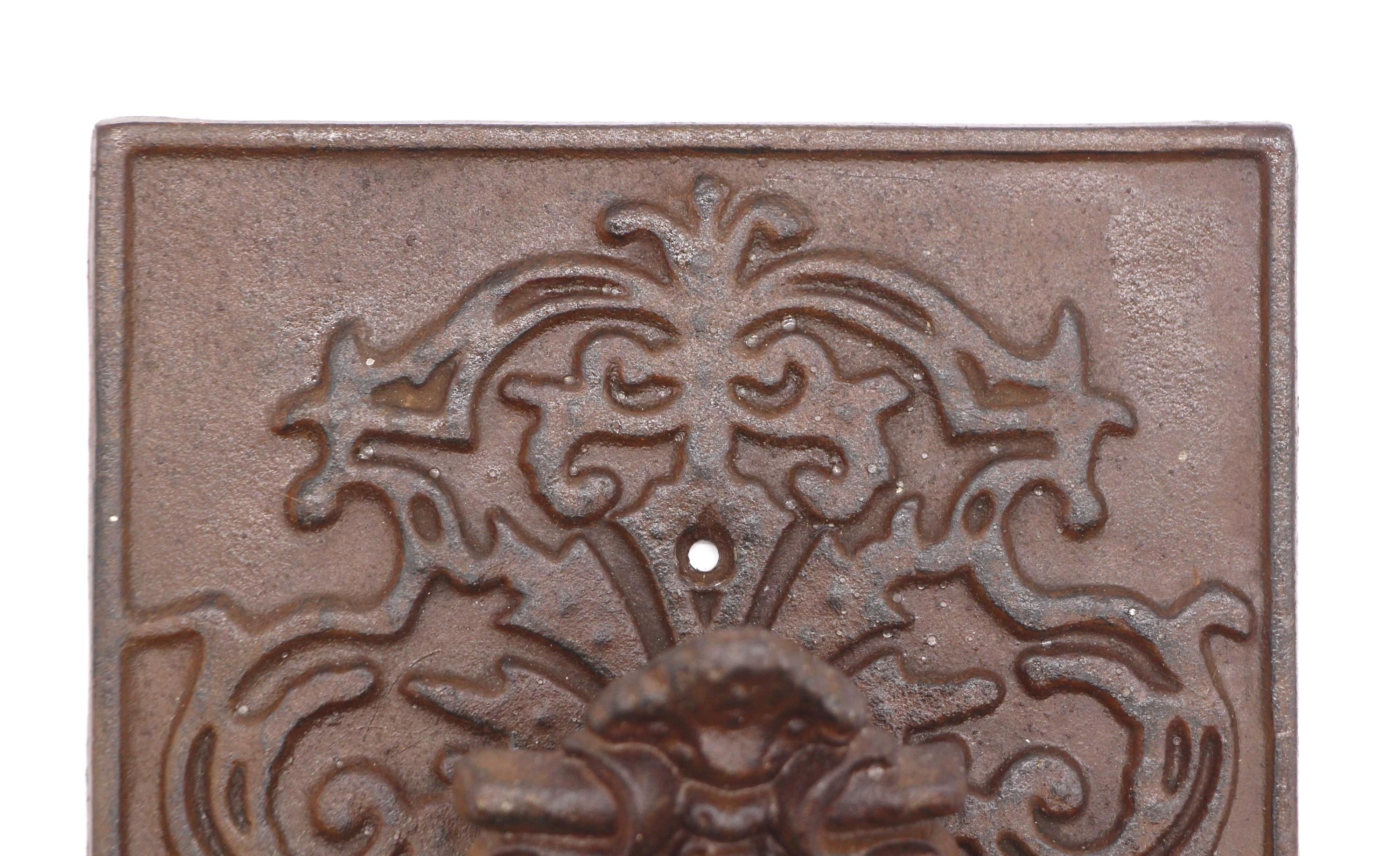 Early 20th century ornate rectangular cast iron door knocker. Center shows a figural griffin. This can be seen at our 400 Gilligan St location in Scranton, PA.