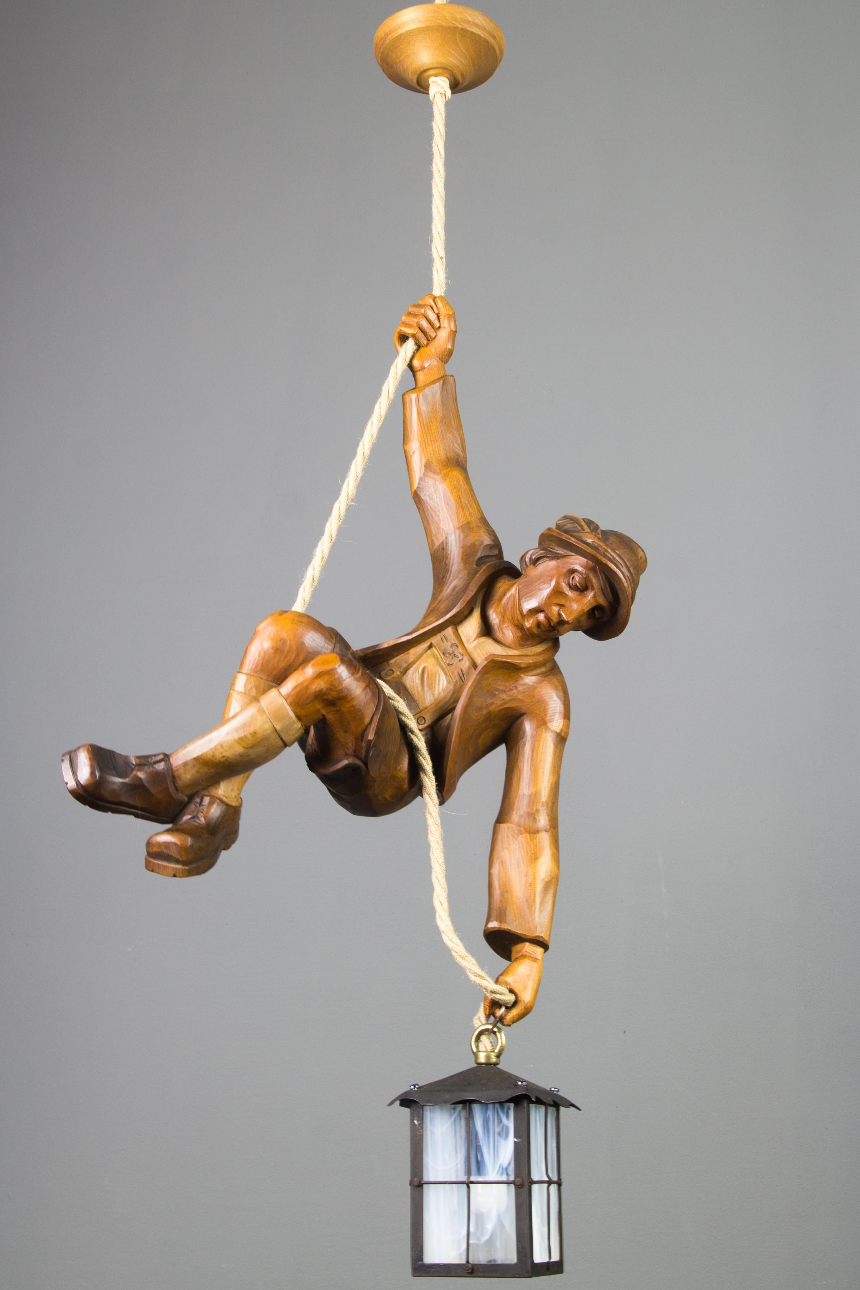 Wonderful German figural pendant lamp features a hand carved figure of a mountain climber. The detailed carved wooden mountaineer is holding onto a rope and holding a lantern in one hand. The figure is in beautiful brown colors and the lantern