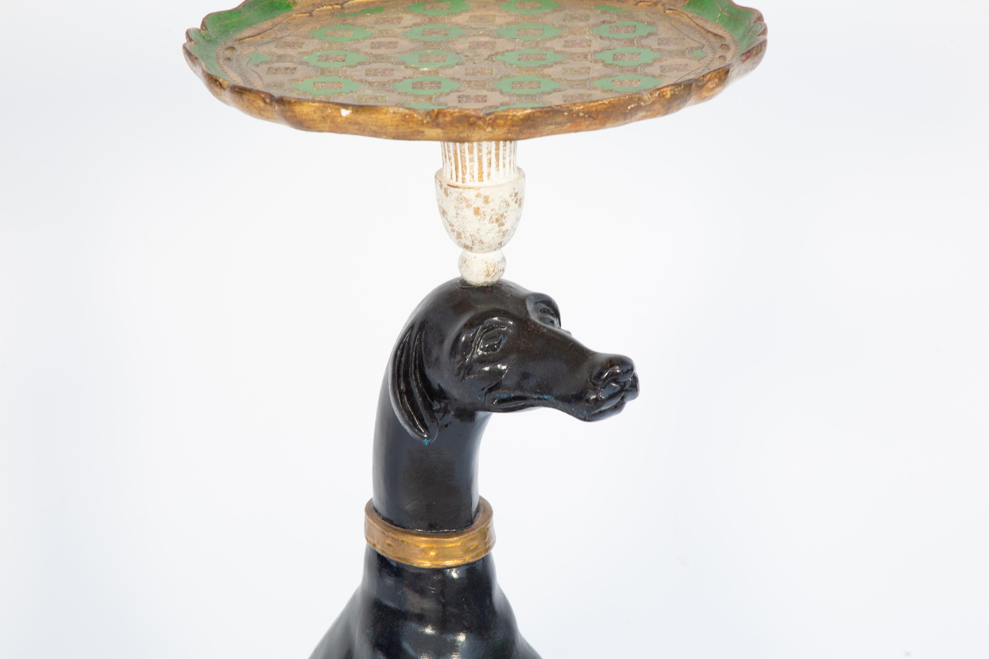 Table à plateau figurative, un chien whippet laqué noir assis sur une base conforme en bois décorée de godrons dorés, le chien tient en équilibre sur sa tête un plateau rond en bois de Florentine. 

Veuillez nous contacter pour obtenir d'autres