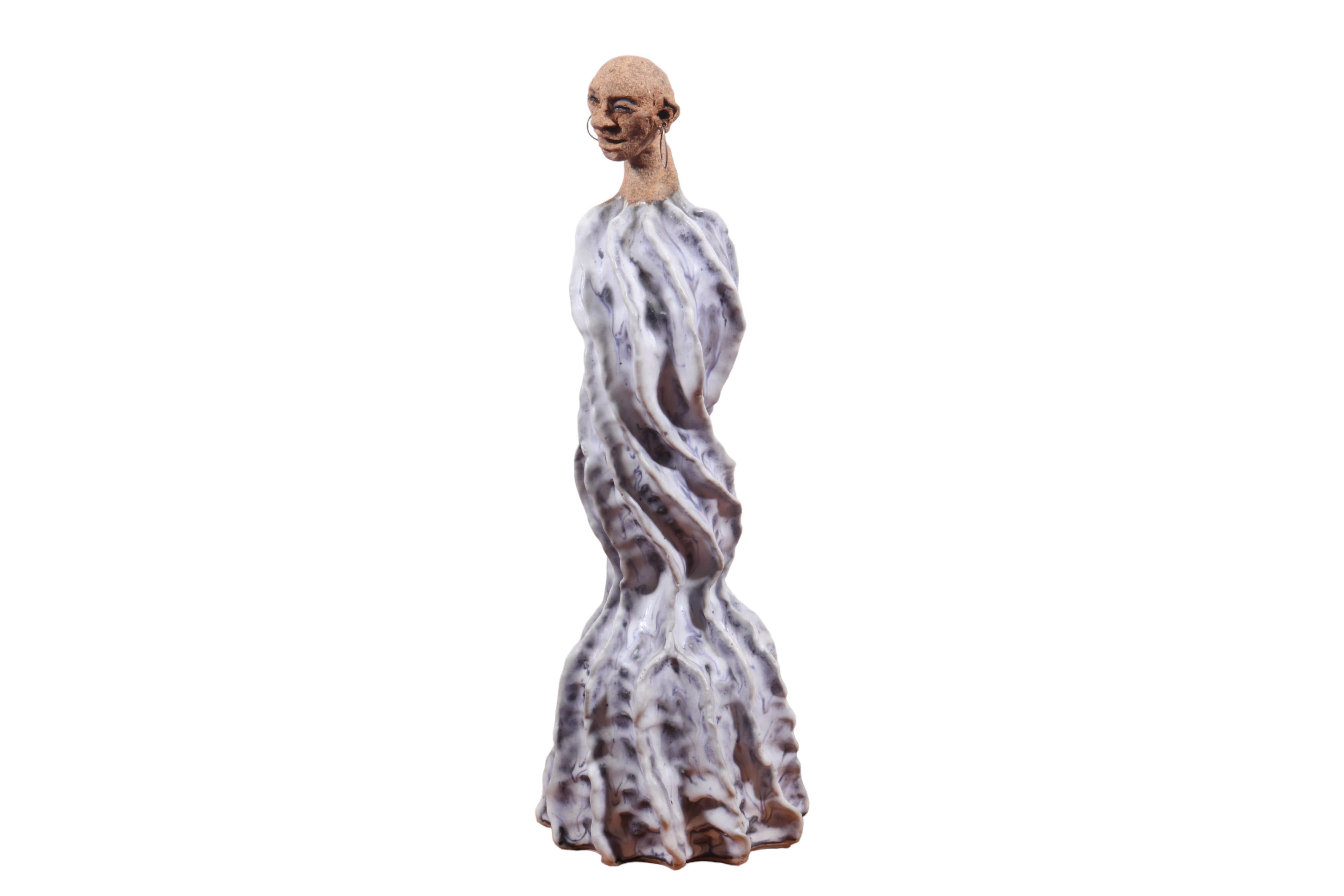 A contemporary figural ceramic sculpture by New York ceramicist Joan Stuart. A feminine smiling head beams down from above a tall wave form. The head has a rough stone like texture in stark contrast to the glossy deep ridges of the wave like body.