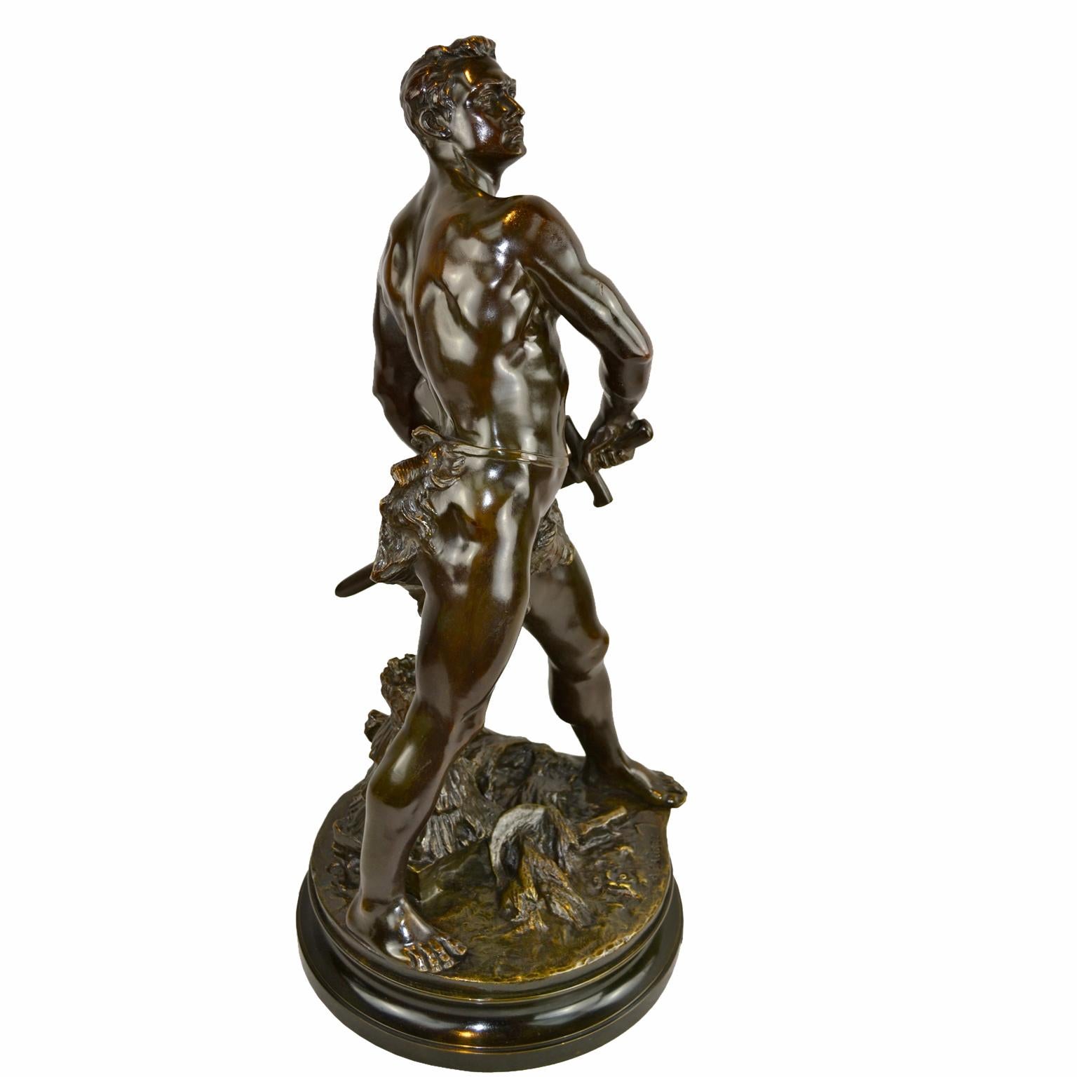 Un bronze magnifiquement coulé représentant un jeune homme musclé au torse nu dans une pose classique, ne portant qu'une peau de bête autour de la taille. Il est en train de sortir une épée de son fourreau alors qu'il se tient au-dessus d'une balle