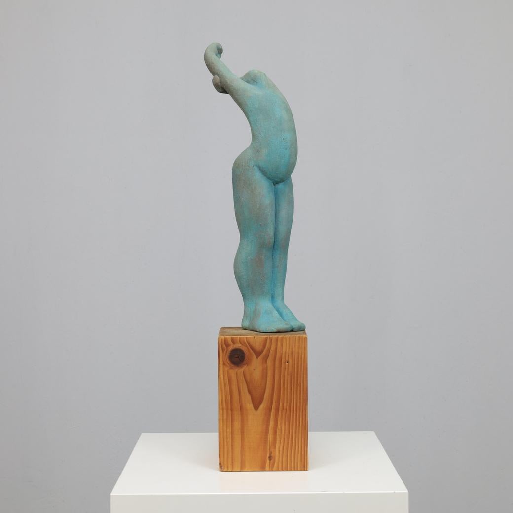A striking figurative sculpture by Dutch artist Francine Govers, created in the 1990s. Rendered in tinted concrete with a softly weathered turquoise surface, the piece captures a dynamic female form in a moment of upward movement both grounded and