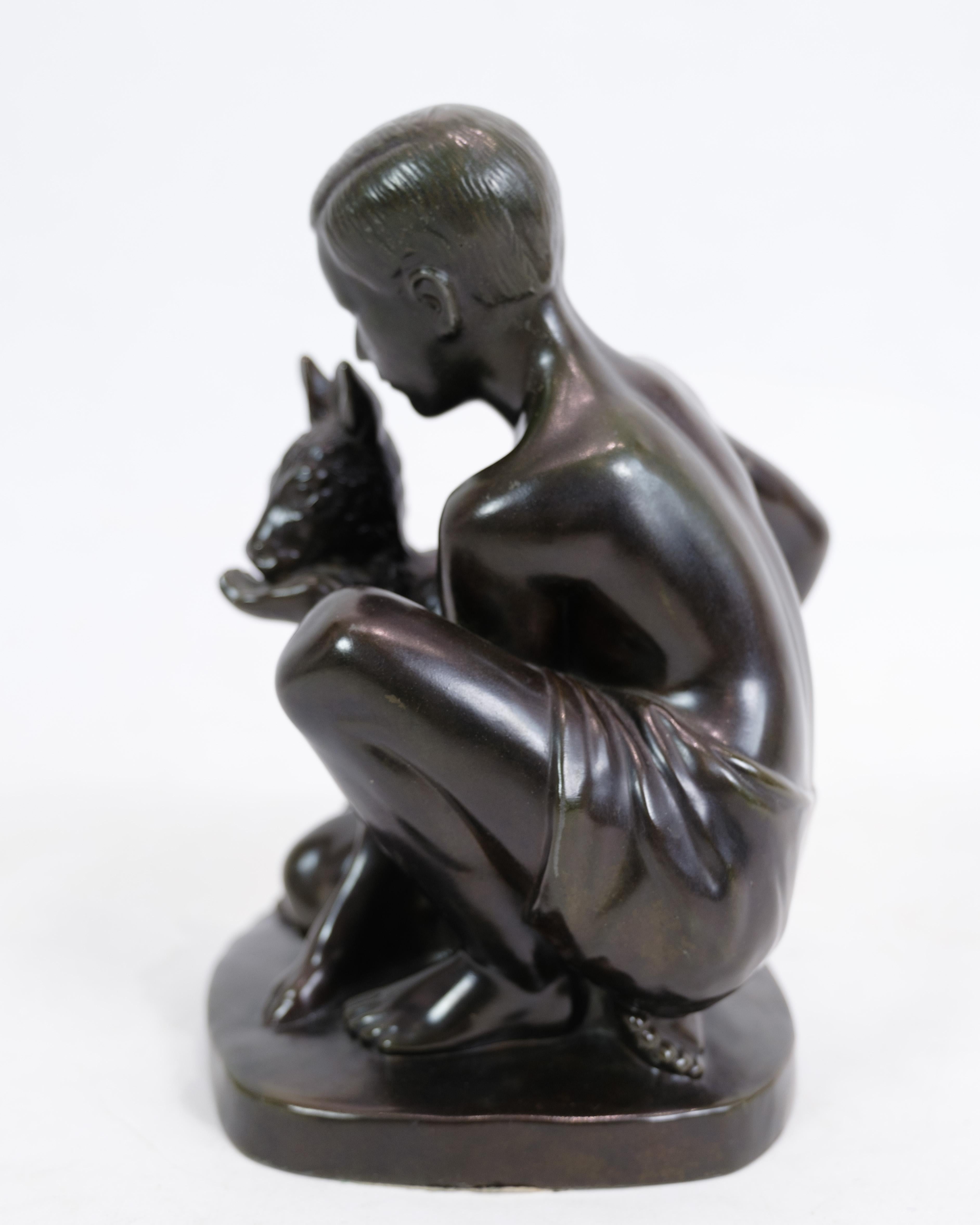 Die Figur von Just Andersen stellt eine wunderschön gearbeitete Skulptur dar, die einen Jungen und ein Hirschkuh-Motiv zeigt. Es ist mit der Modellbezeichnung Just A D2318 gekennzeichnet. Diese Skulptur strahlt eine gewisse Schlichtheit aus und
