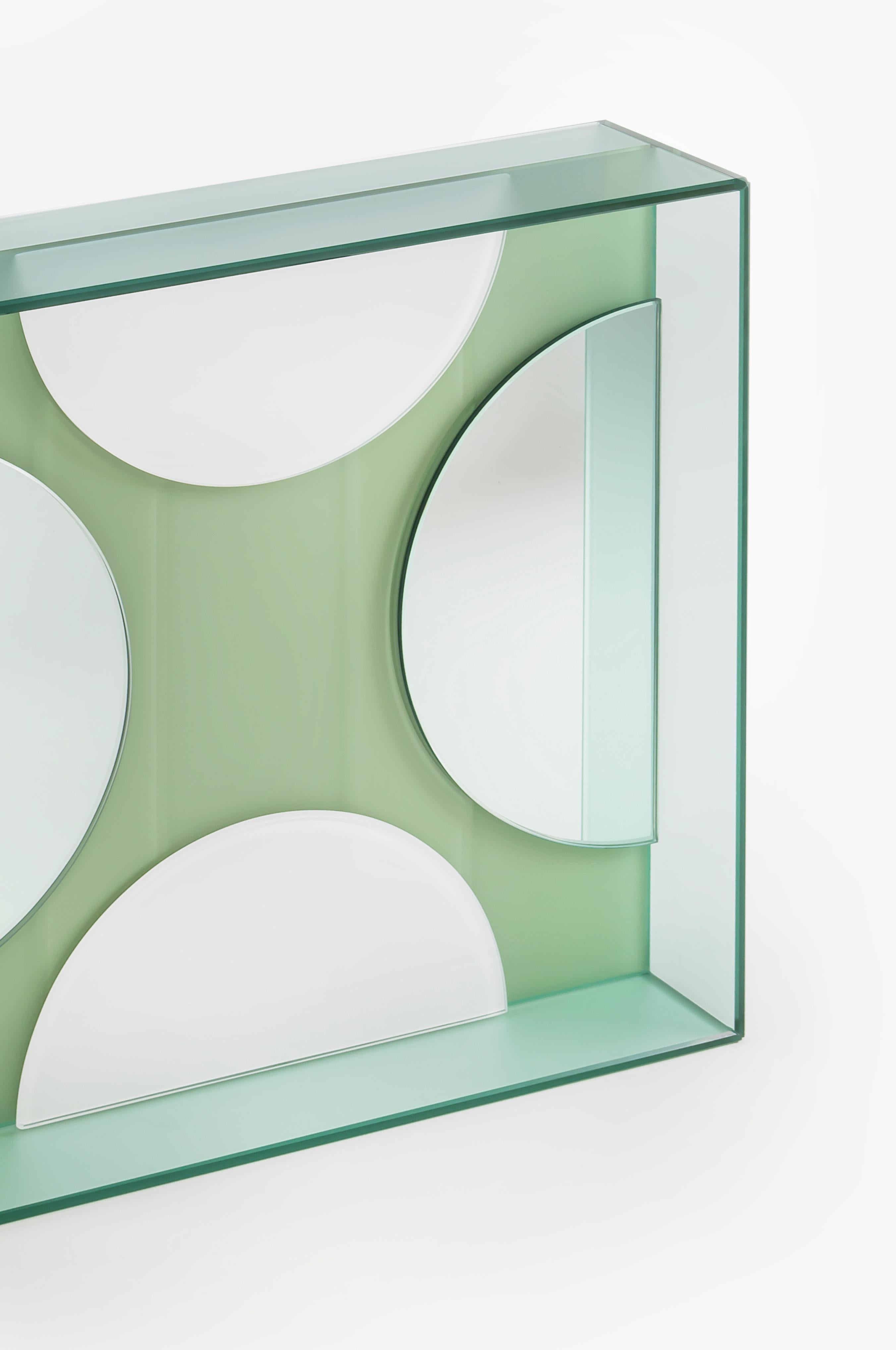 This mirror for wall or tabletop juxtaposes matte, glossy and colored reflective glass in an artful arrangement to create an unconventional, striking accessory that is as much a work of art as a mirror.