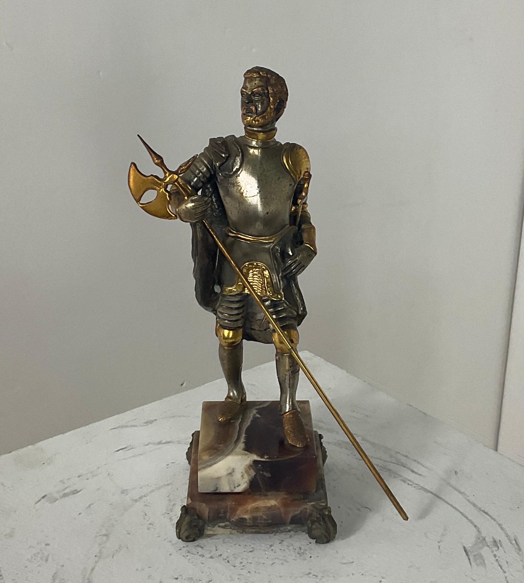 La figura di un cavaliere britannico in veste militare ,realizzata dal riconosciuto maestro italiano Giuseppe Vasari (1934 - 2005) presumibilmente negli anni Settanta. Marcato sul retro. Bronzo con placcatura in oro e argento, base in onice naturale.