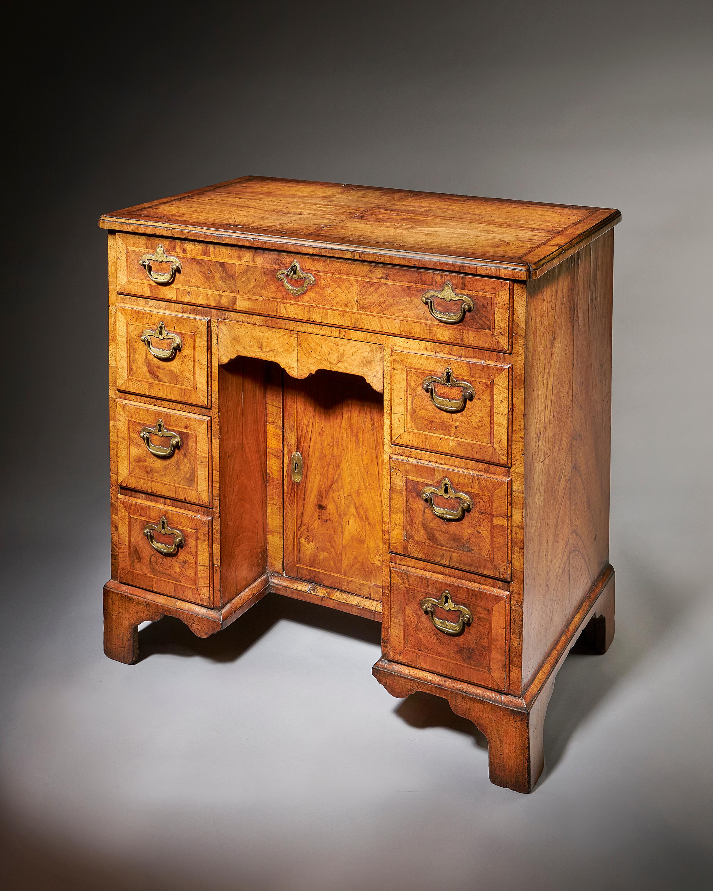 A fine George II figured walnut kneehole desk attributed to Elizabeth Bell & Sons, 1740-1758.

The superb quarter veneered figured walnut top is bordered by a fine feather stringing, cross-banded and edged with cross-grain ovolo mouldings on