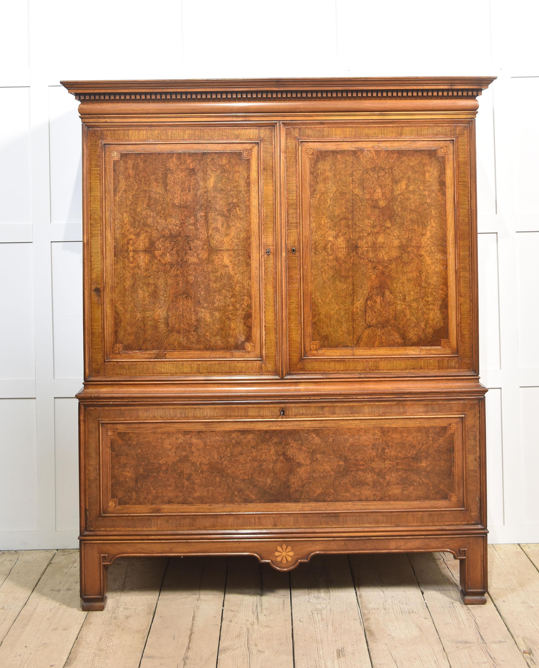 Armoire de presse de belles proportions. La corniche moulurée surplombe les grandes portes à panneaux en noyer bien dessinées qui s'ouvrent pour révéler un grand placard entouré de quatre tiroirs. La partie inférieure est dotée d'une porte de