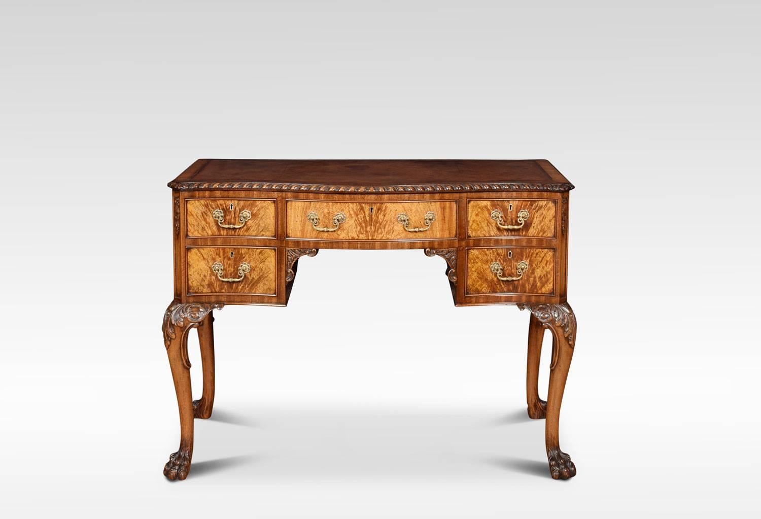 A figured walnut Queen Ann style writing desk, the shaped top with inset brown leather writing surface inclosed by carved moulded edge. Above an arrangement of five drawers with brass handles, raised up on acanthus cabriole legs terminating in hairy