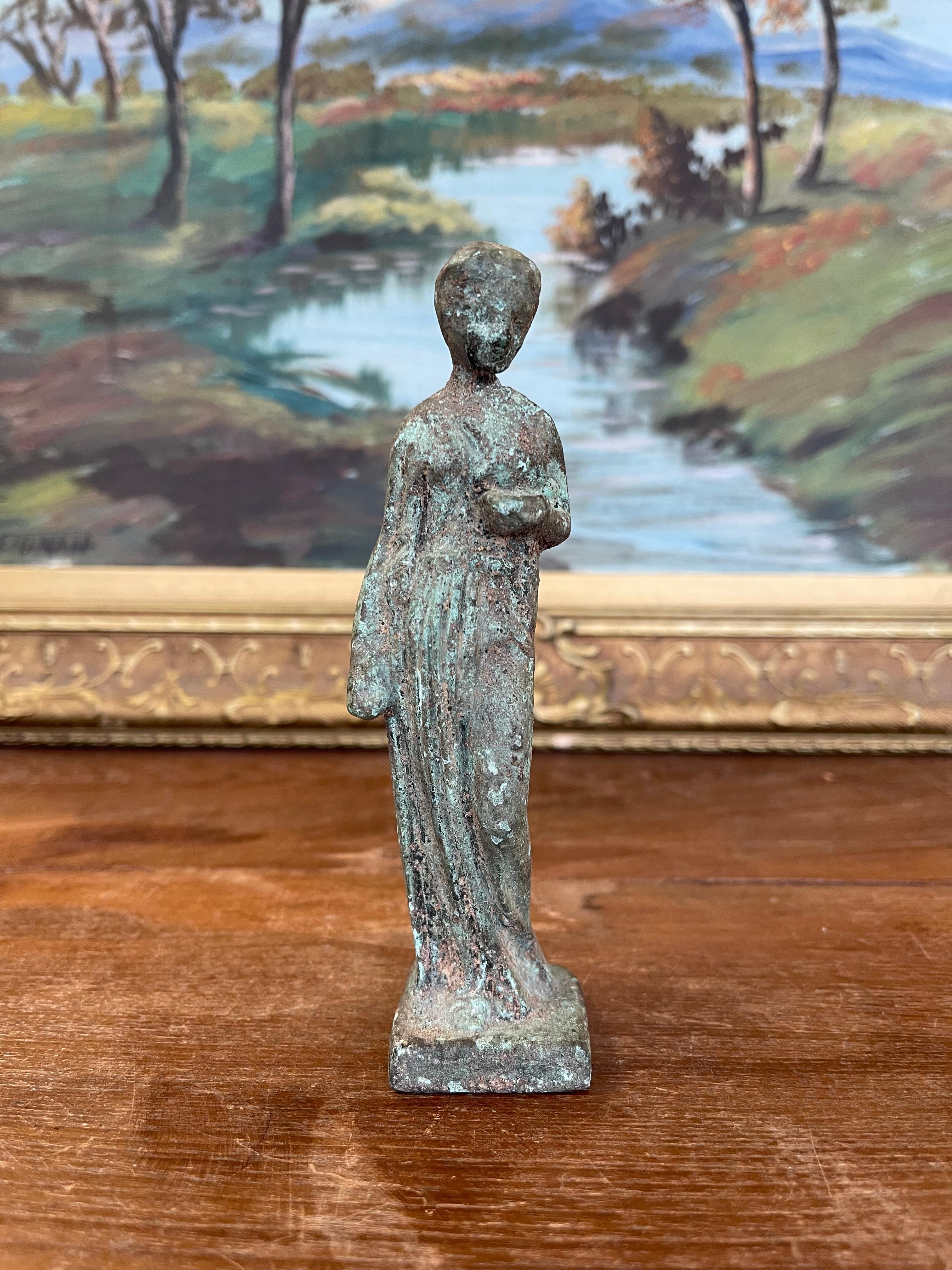  Figurine détaillée représentant une figure féminine debout, vêtue d'une longue draperie fluide inspirée des formes classiques. Le chiffre  est posée avec un bras le long du corps et l'autre légèrement plié vers la taille, suggérant un geste