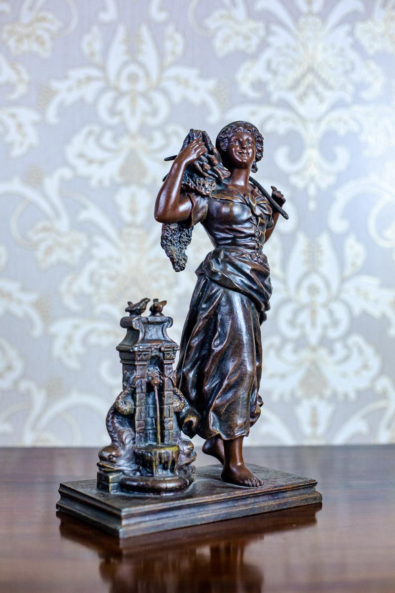 We present you a bronzed zamak figurine, depicting a young woman with a basket of fish and a stone spigot.
The whole is placed on a rectangular, metal pedestal.

All signed by Ernest Rancoulet (a French sculptor who lived in the years