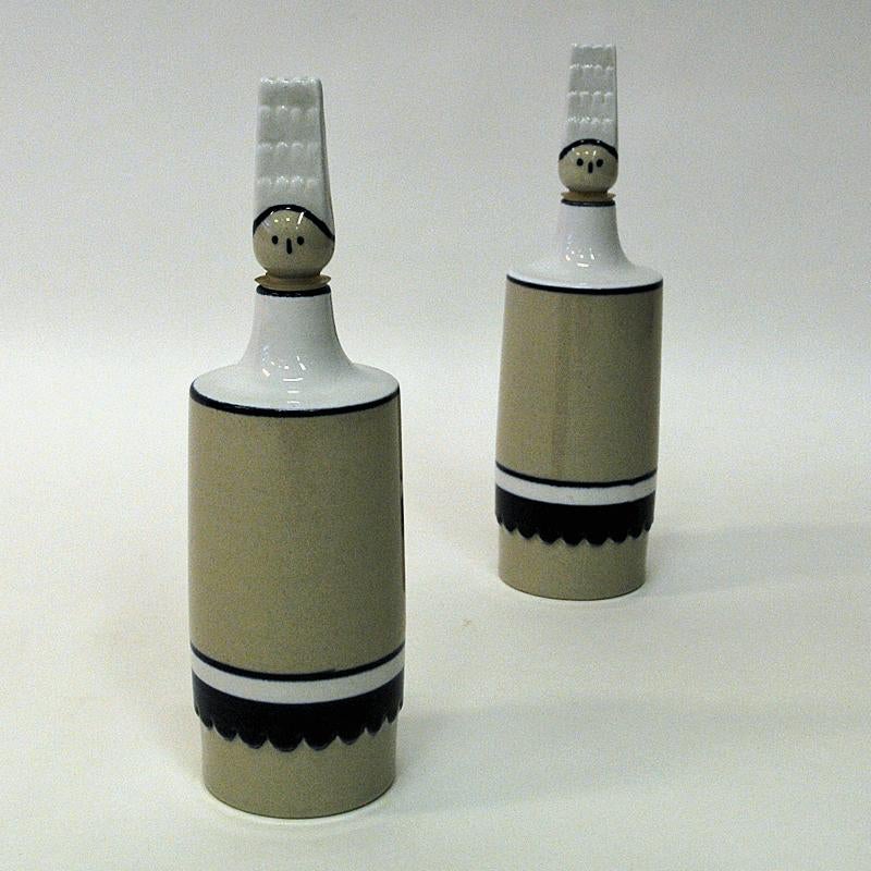 These handmade and rare oil and vinegar bottles are made as people in glazed stoneware by Höganäs - Sweden 1950s. The Top caps are designed as heads. Beige base color with white and blue edge decorations. Glazed finnish. Just lovely on the kitchen