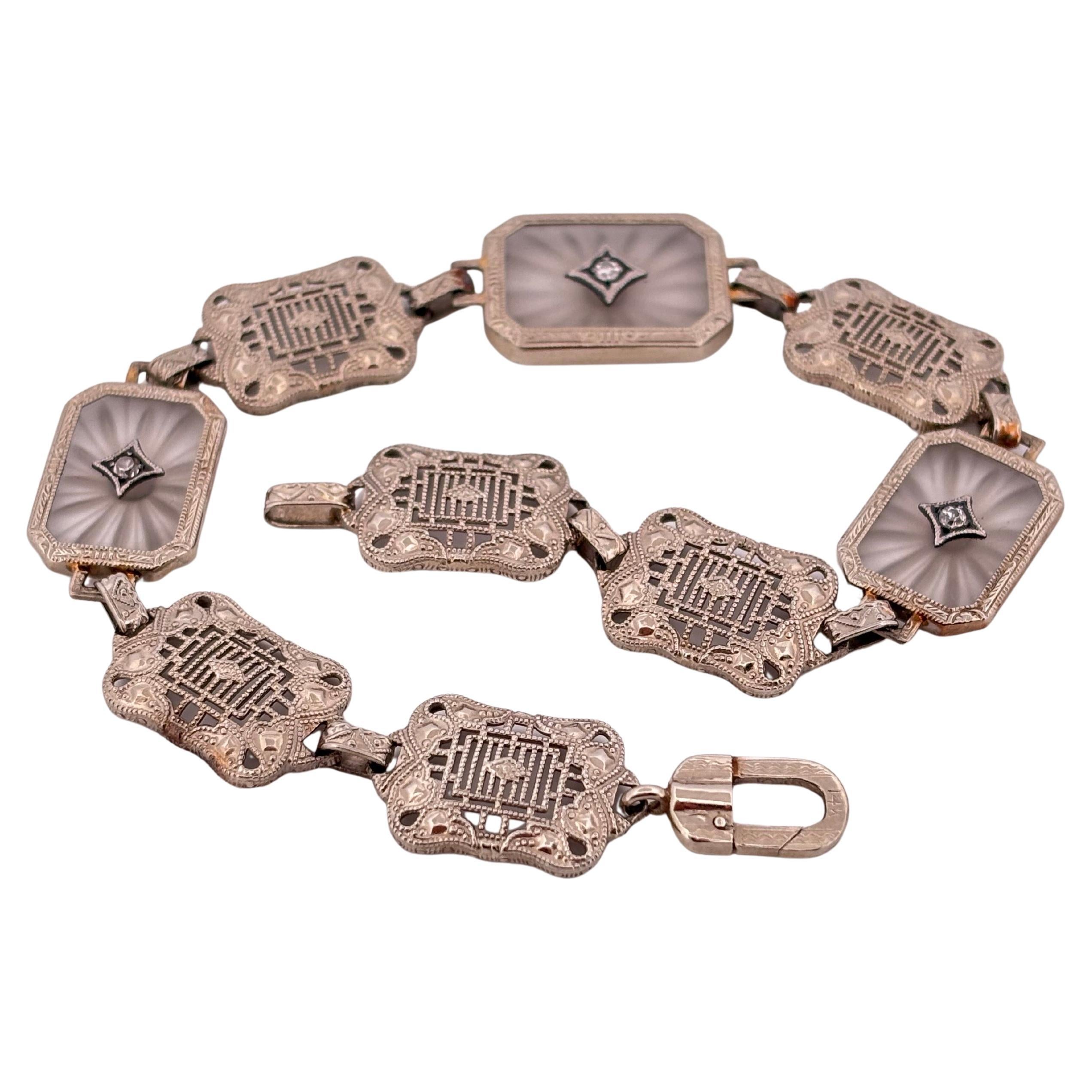 Questo squisito bracciale di ispirazione Art Deco è finemente realizzato in oro bianco 14 carati e mostra una straordinaria combinazione di arte in filigrana ed eleganti accenti di pietre preziose. Lungo 7,5 pollici e largo 12,75 mm, è disegnato con