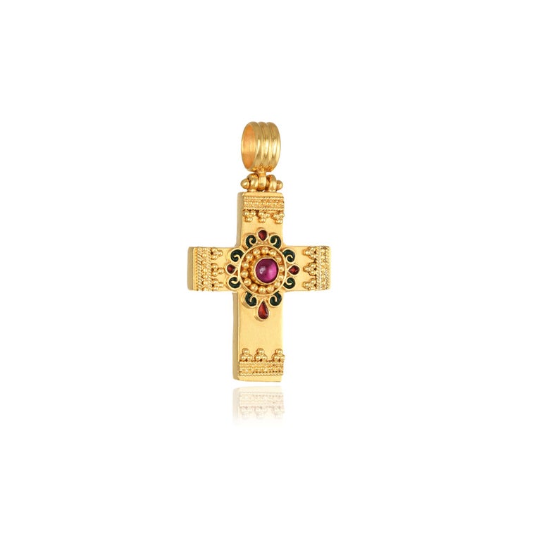 Byzantine cross pendant handcrafted in 22Kt yellow gold, featuring a round tourmaline center and two colours of enamel, red and green. This pendant is braided using the ancestral techniques of granulation and filigree. The red and the green colours