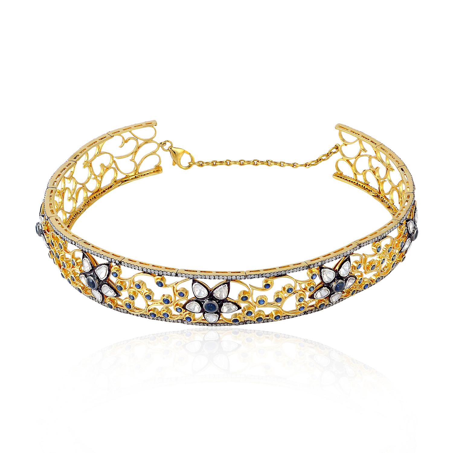 This exquisite choker necklace boasts a delicate filigree design crafted in 18k gold and silver, adorned with dazzling diamonds and sapphires. Its intricate and detailed craftsmanship makes it the perfect choice for a formal event or a special