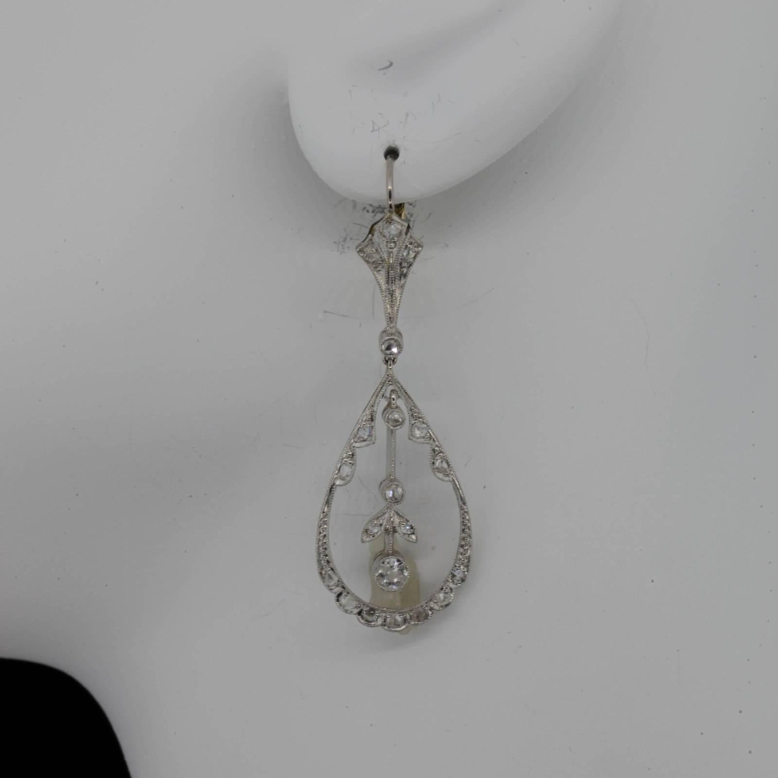 These pretty Deco style dangling earrings are fabricated in platinum and 18KT yellow gold.  The open work pear shape earrings are accented with 0.72 carat of Rose Cut Diamonds and are set with lever backs; they dangle  1 3/4