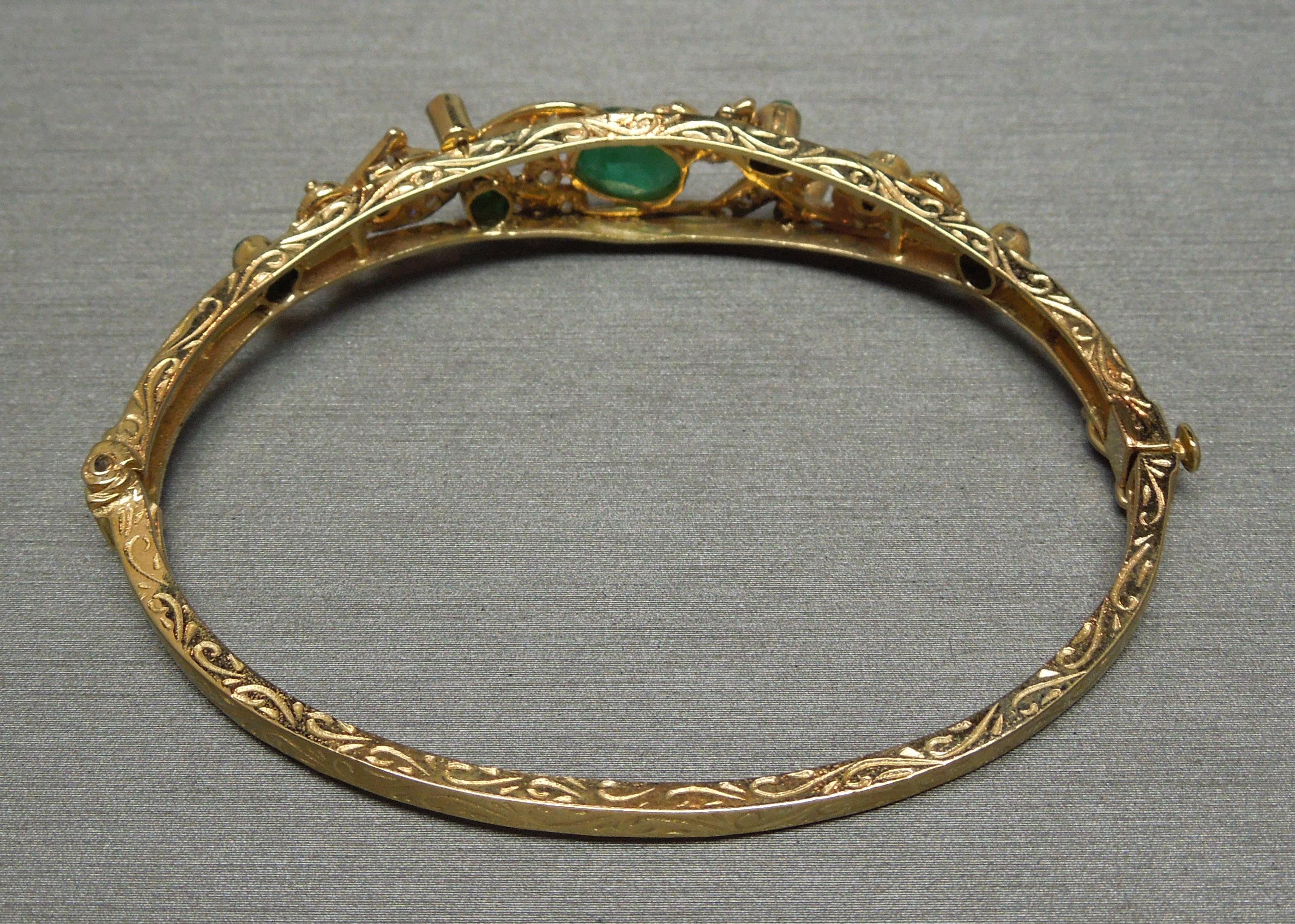 This 14 Karat Yellow Gold Filigree Emerald & Diamond Bangle Bracelet borders between Edwardian inspirations with a slight Art Deco flare. In an Oval shaped bangle for comfort as well as to keep the jeweled section centered on the wrist, as opposed