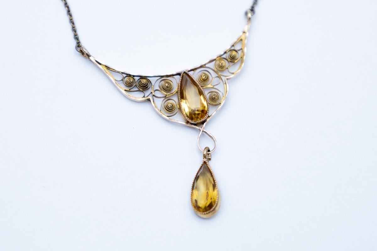 Beautiful necklace decorated with the filigree method, an artistic jewelry technique popular in the early 20th century, creating subtle spirals and swirls.

Decorated with two teardrop-shaped citrines.

The whole creates an extremely delicate,