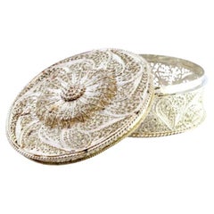 Filigree silver box with reliefs and cutouts, resting on three feet