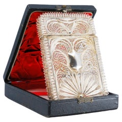 Filigree silver card case with a central monogram card and hinged lid