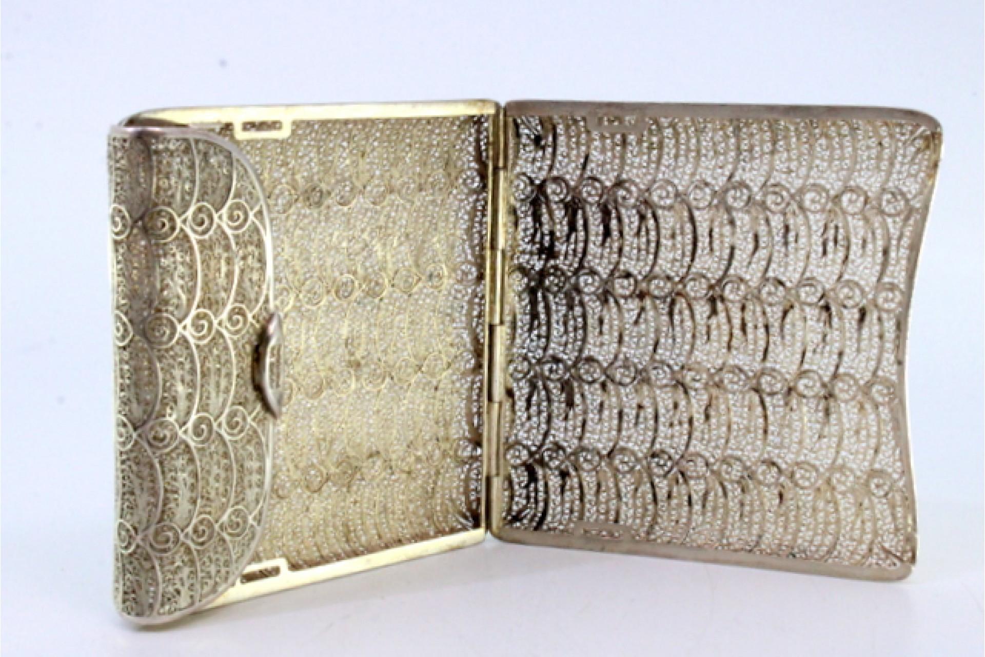 Description: Filigree silver cigarette case with spring-loaded, hinged lid. Metal: Silver. Origin: Portuguese. Brand: Absent. Weight: 108.64 grams. Dimensions: 8.5cmx9cm. Content: 833/1000. Assay Mark: Absent. Additional information: Good condition.