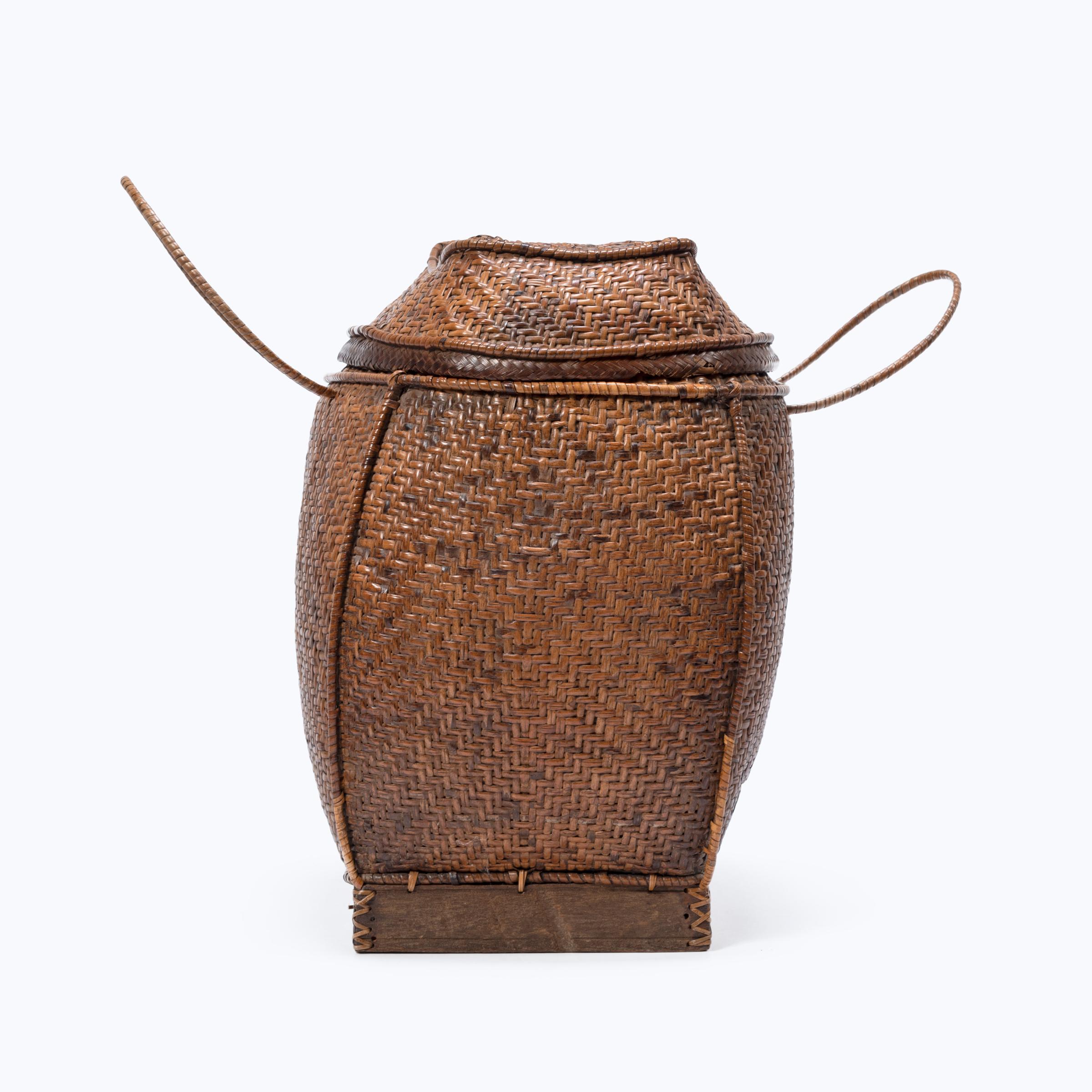 Basket making is an ancient and humble craft, but in the hands of a skilled weaver a simple reed basket can become a truly beautiful work of art. Handmade in the Philippines, this lidded basket with arched handles was once used for gathering