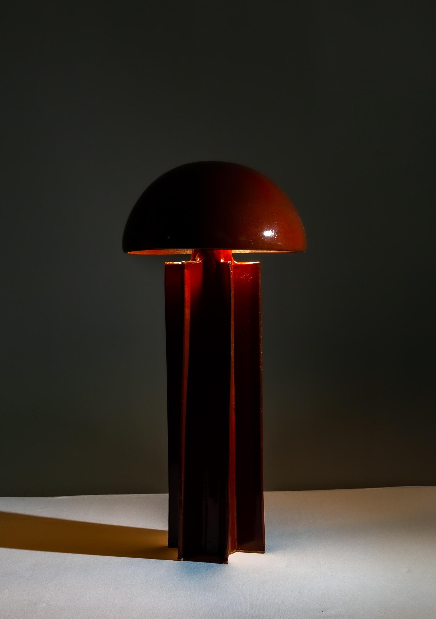 Lampe de table FIN en Oxblood Lustre - une déclaration captivante dans un rouge riche et opulent. La luxueuse glaçure, d'un cramoisi profond rappelant le grenat poli, incarne un savoir-faire raffiné et une sophistication intemporelle. Sa surface