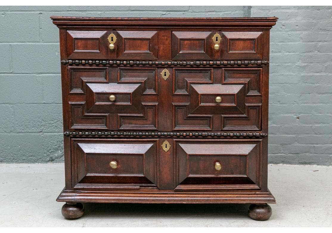 In a dark stain with Fine old patina. The overhanging top made of two planks with a carved edge. The case with two 3-D carved drawers over two long drawers with elaborate carvings with high center rectangles. The middle drawer with angular panels